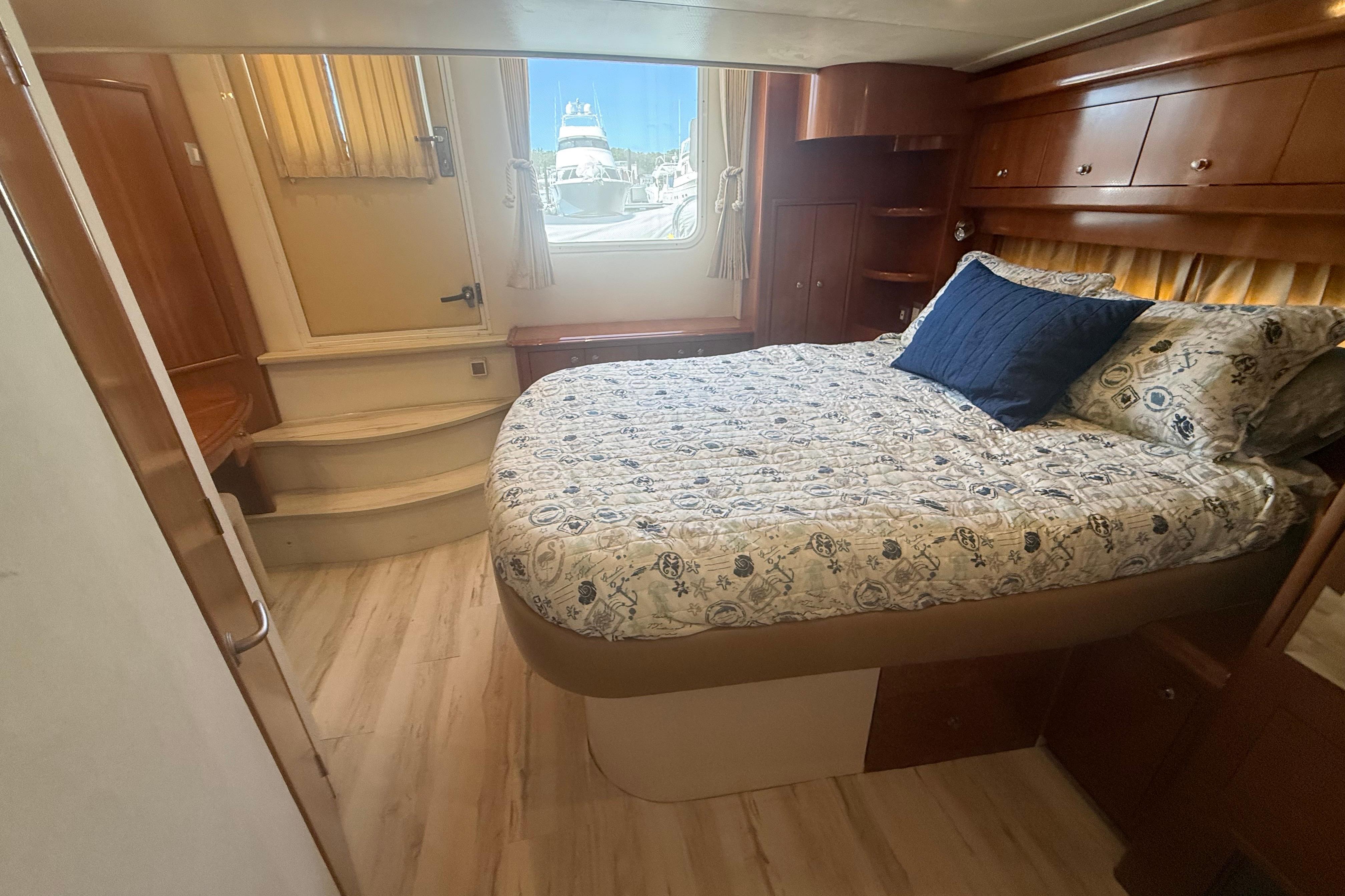 Luxurious 2006 Carver 43 Motor Yacht bedroom with elegant wood finishes and nautical-themed bedding.