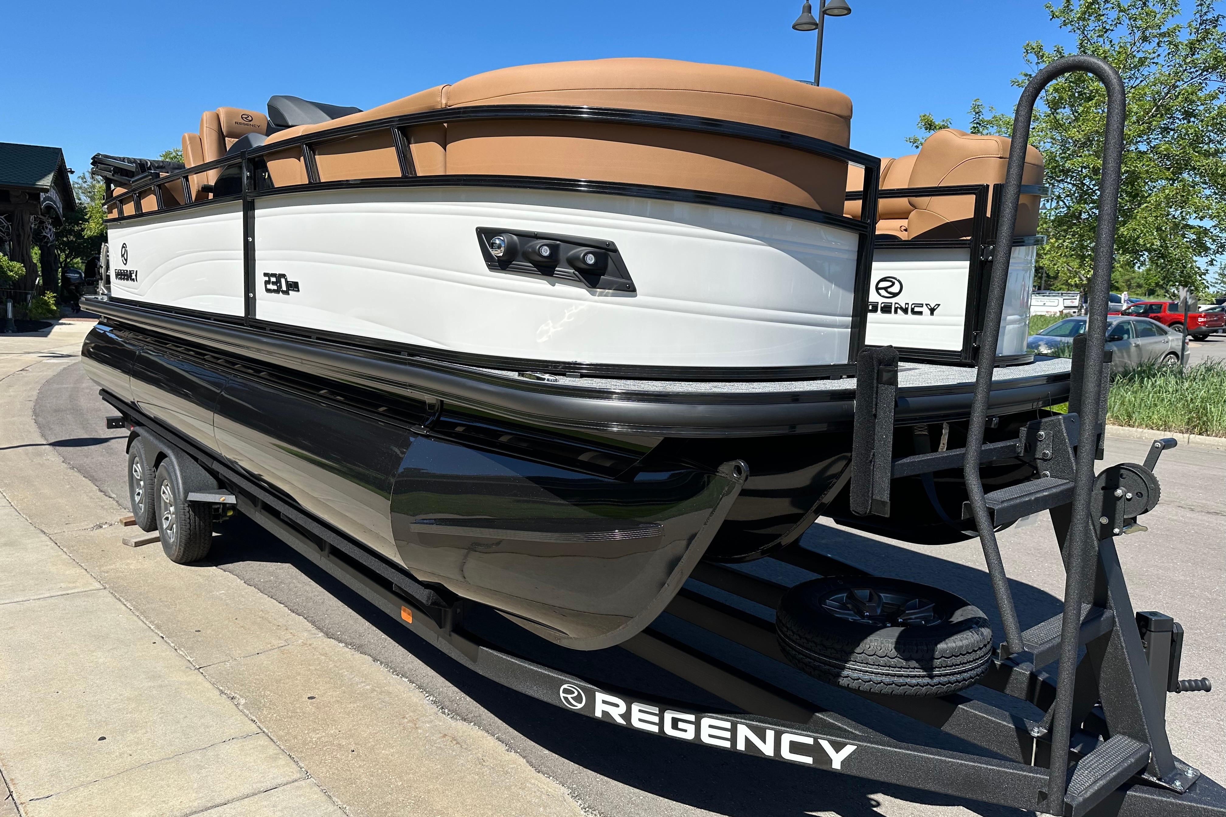 2026 Regency 230 DL pontoon boat on trailer, parked outdoors under clear blue sky.