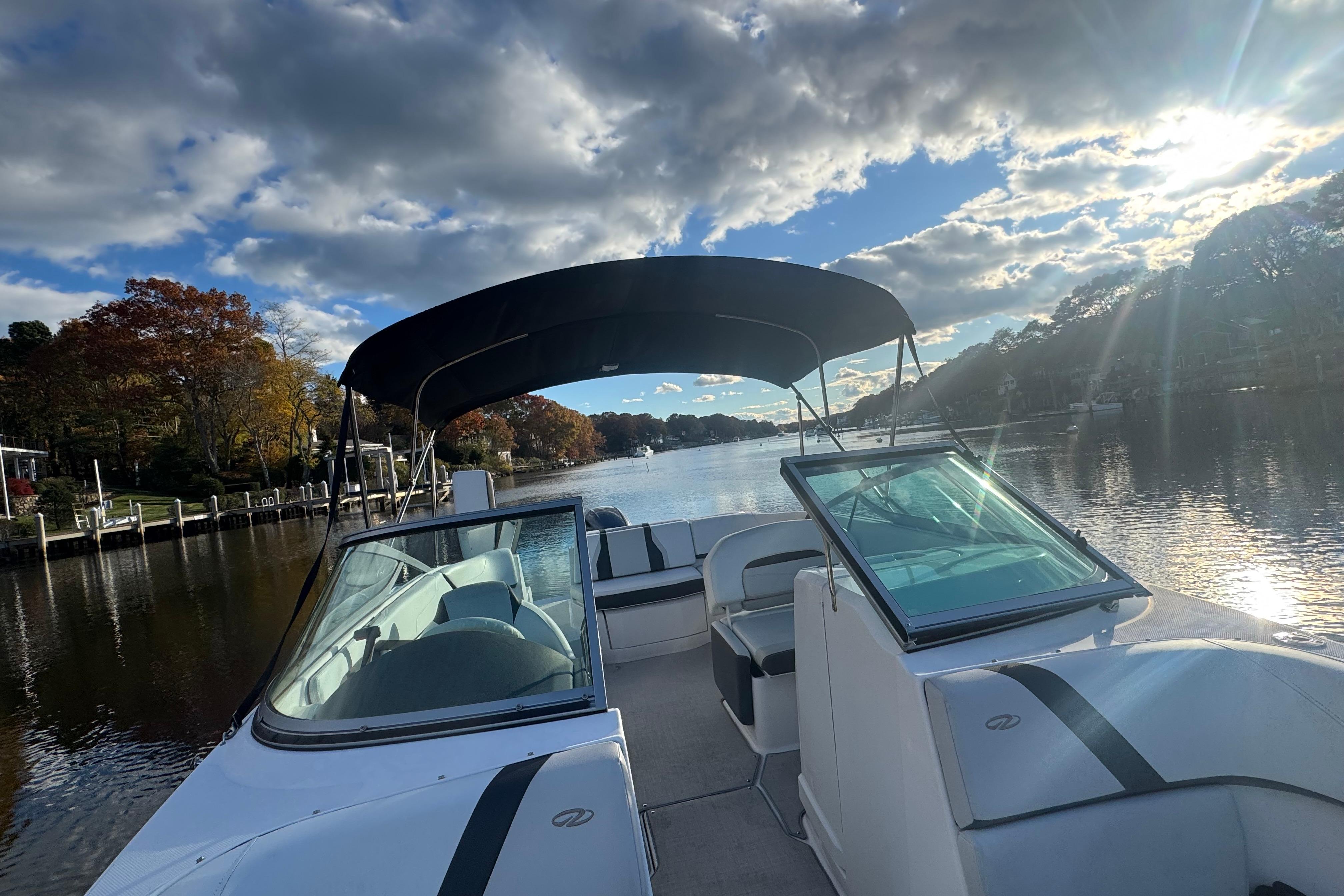 2017 Regal 23 OBX boat on a scenic river with blue sky and clouds.
