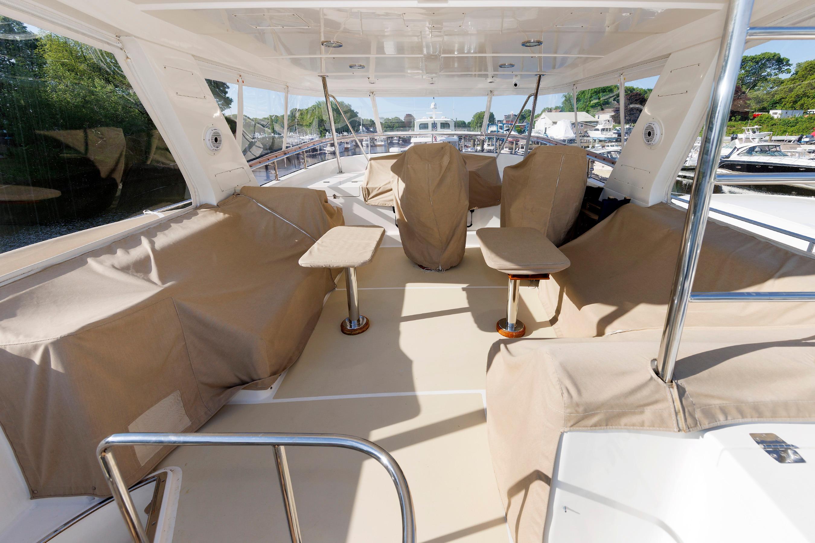 Luxurious 2007 Grand Banks 59 Aleutian RP yacht deck with covered seating and tables.