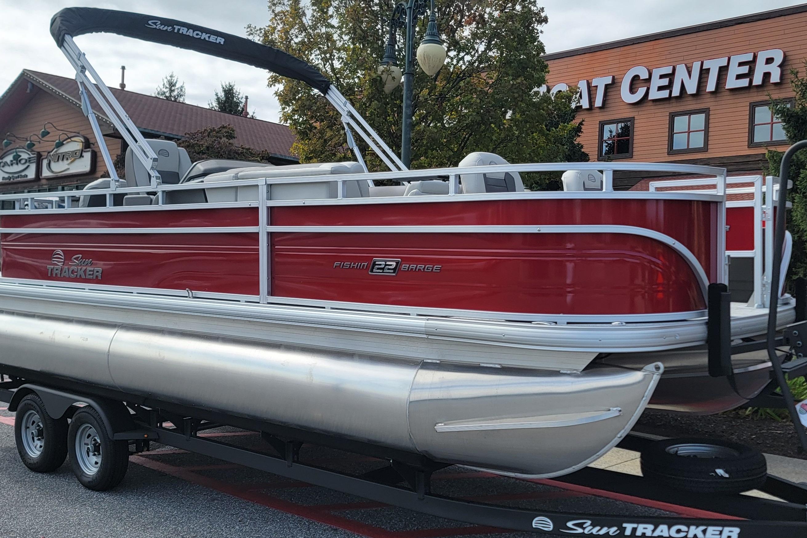 2026 Sun Tracker Fishin' Barge 22 DLX pontoon boat on trailer outside boat center.