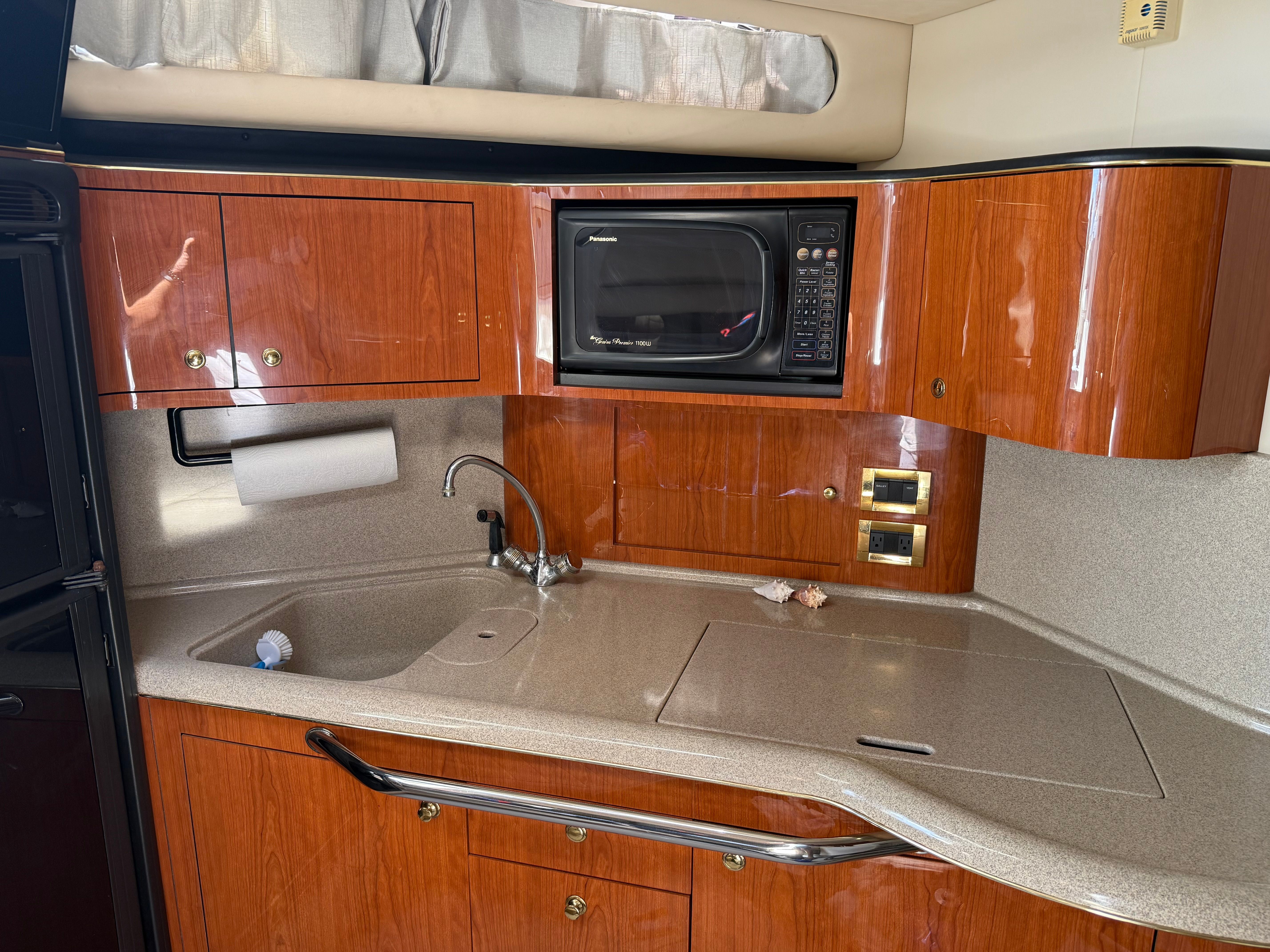 The galley of a 1999 Sea Ray 380 Sundancer with wooden cabinets and a microwave.