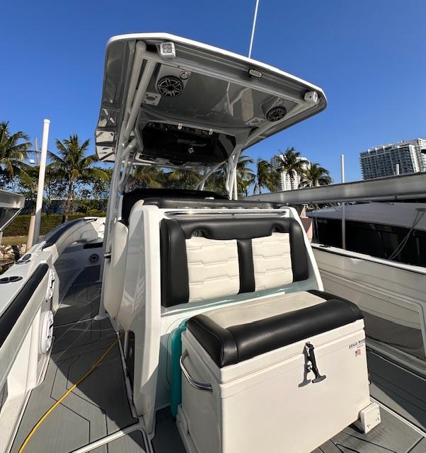 2019 Nor-Tech 340 Sport Center Console boat with seating, palm trees, and clear sky.