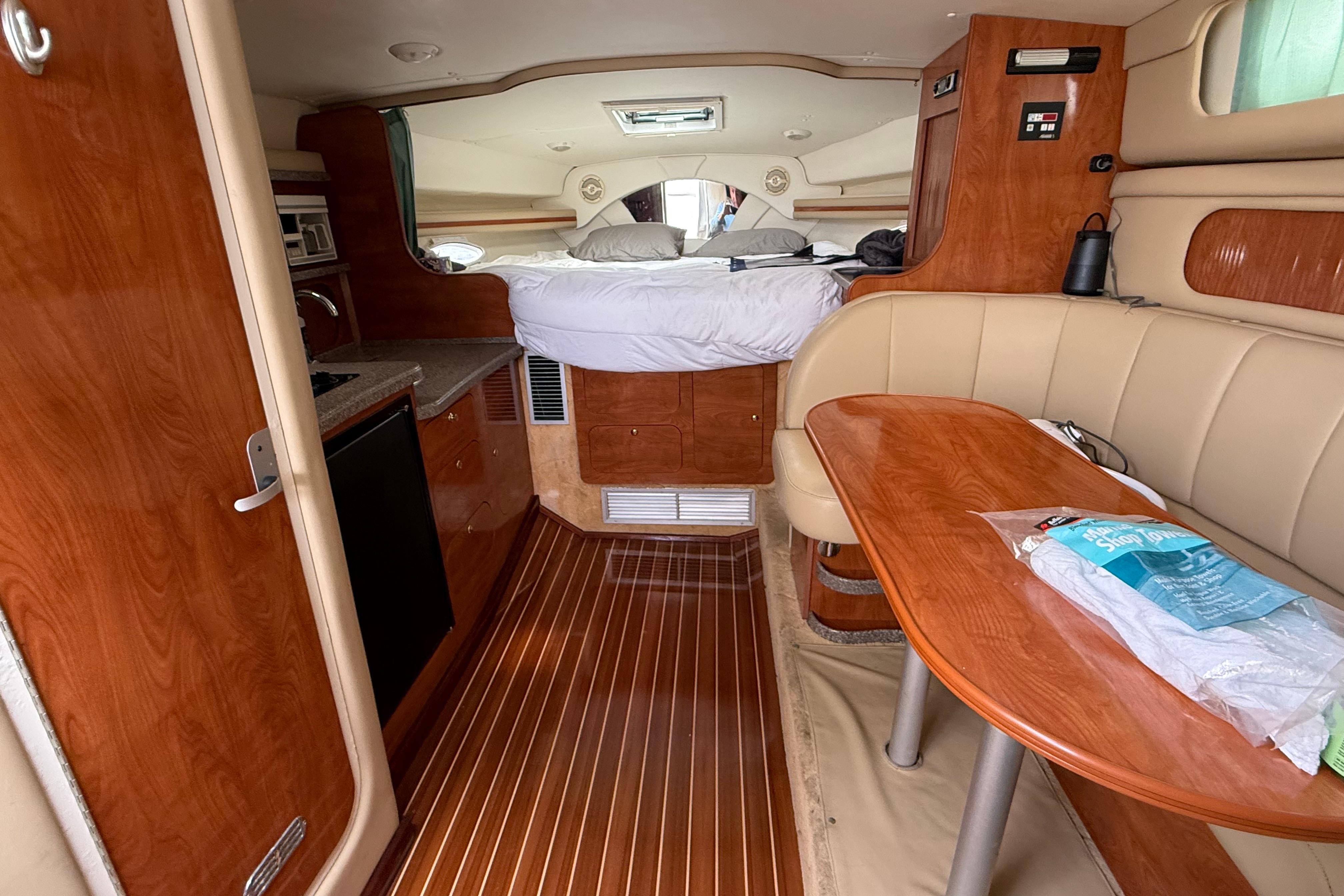2004 Rinker 342 yacht interior with wood finish, kitchenette, and cozy sleeping area.