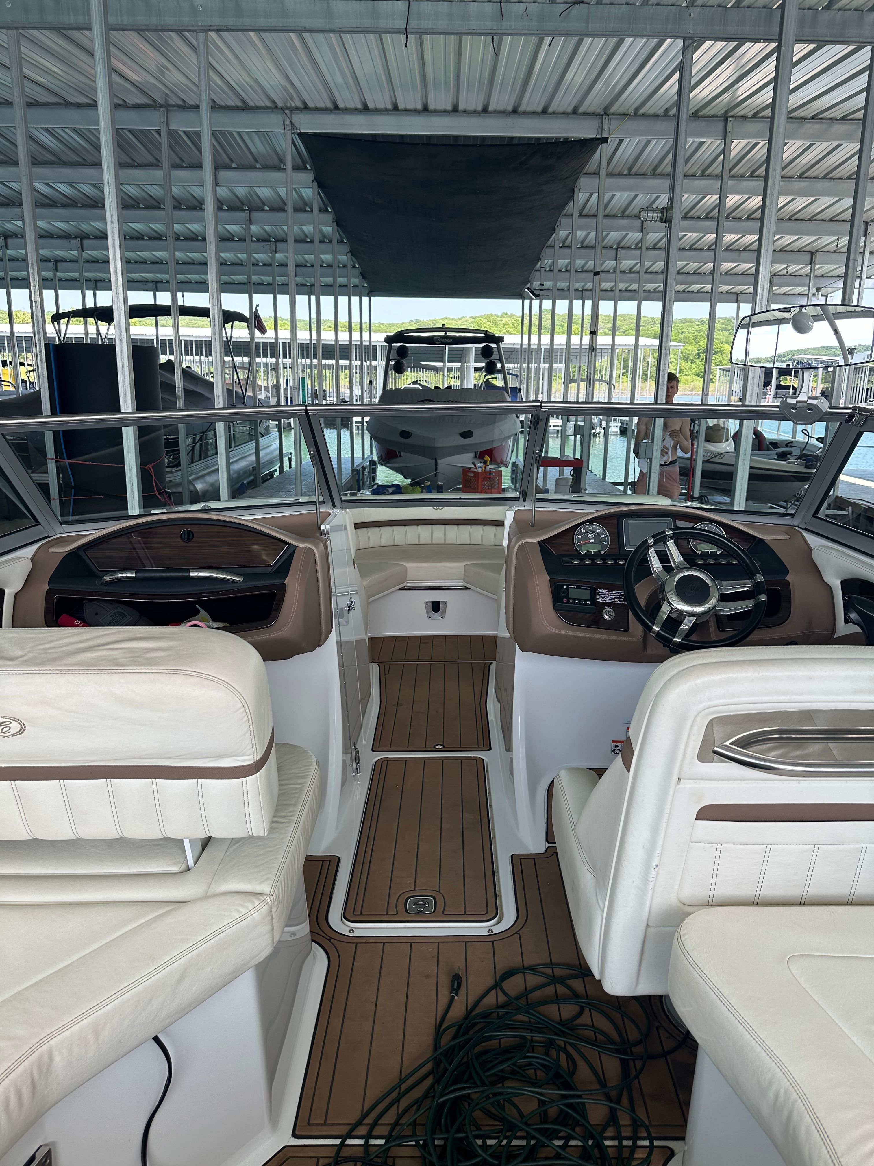 2011 Cobalt A25 in a covered dock. White seats, wooden floor, helm station visible.
