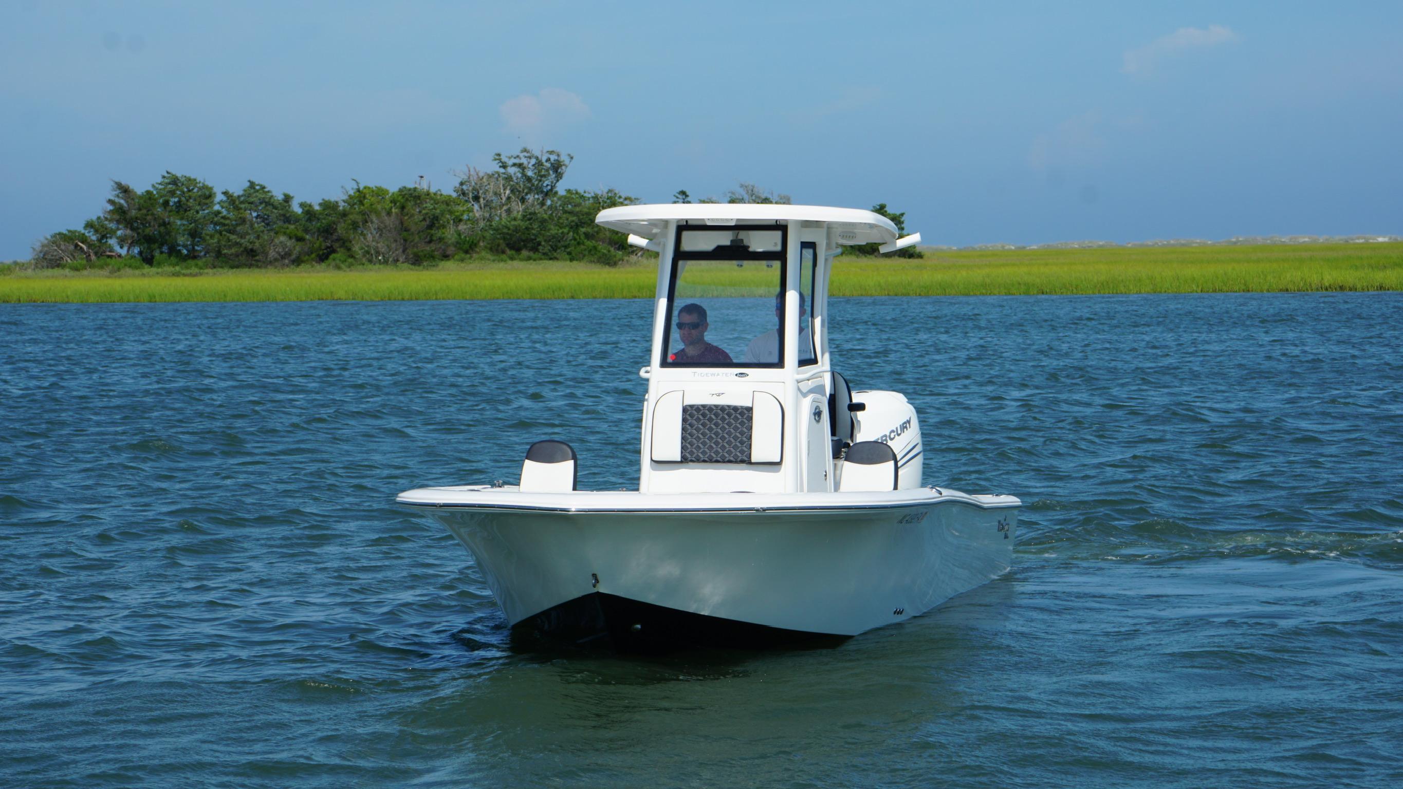 2023 Tidewater 2500CB boat cruising on a serene lake with lush greenery.