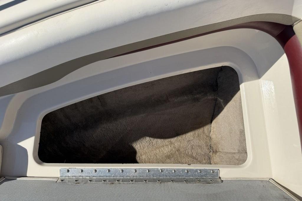 Storage compartment of a 1999 Glastron GT 225 boat, featuring a carpeted interior.