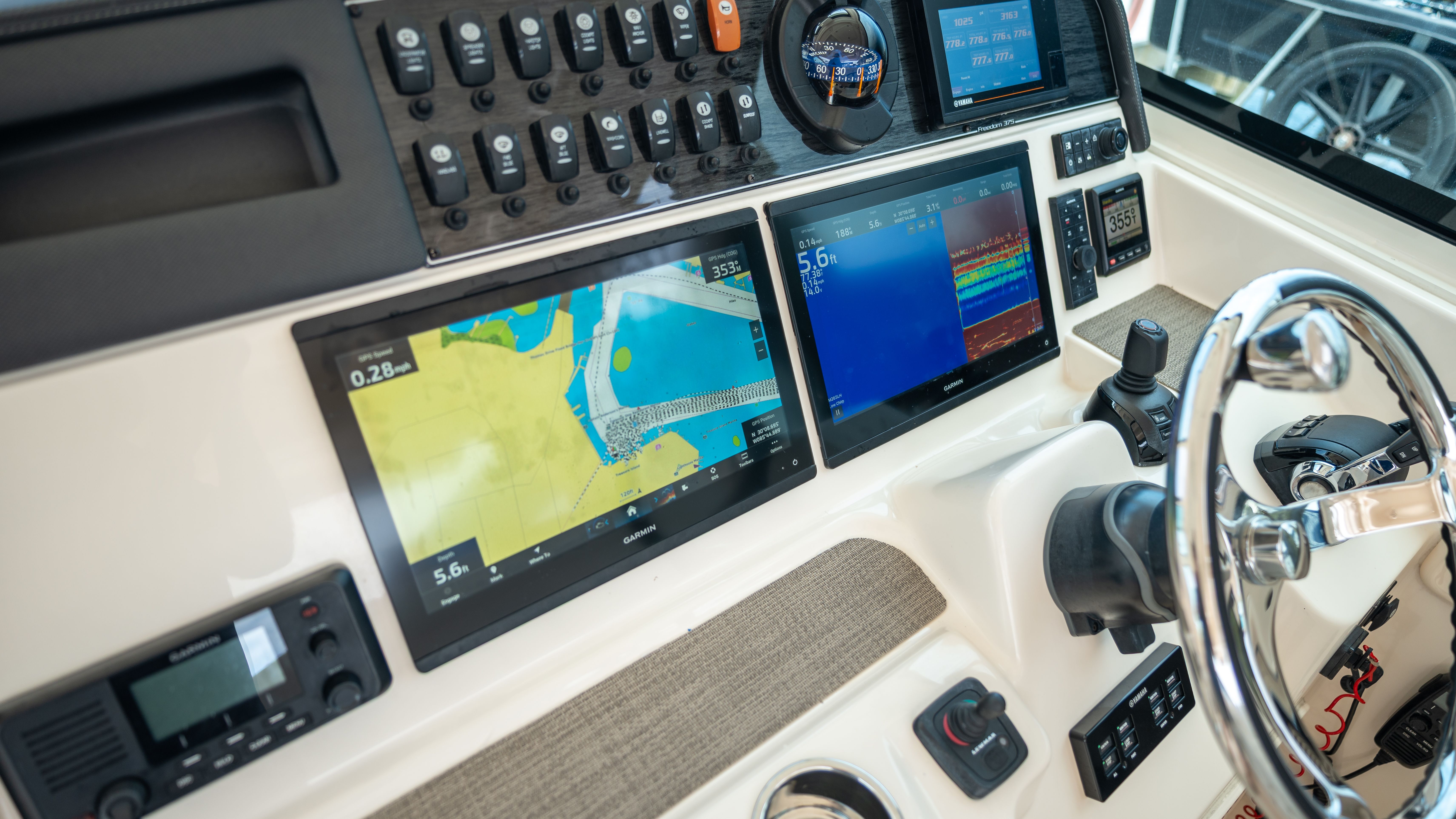The image shows the dashboard of a Grady-White 375 Freedom boat with multiple screens and controls.