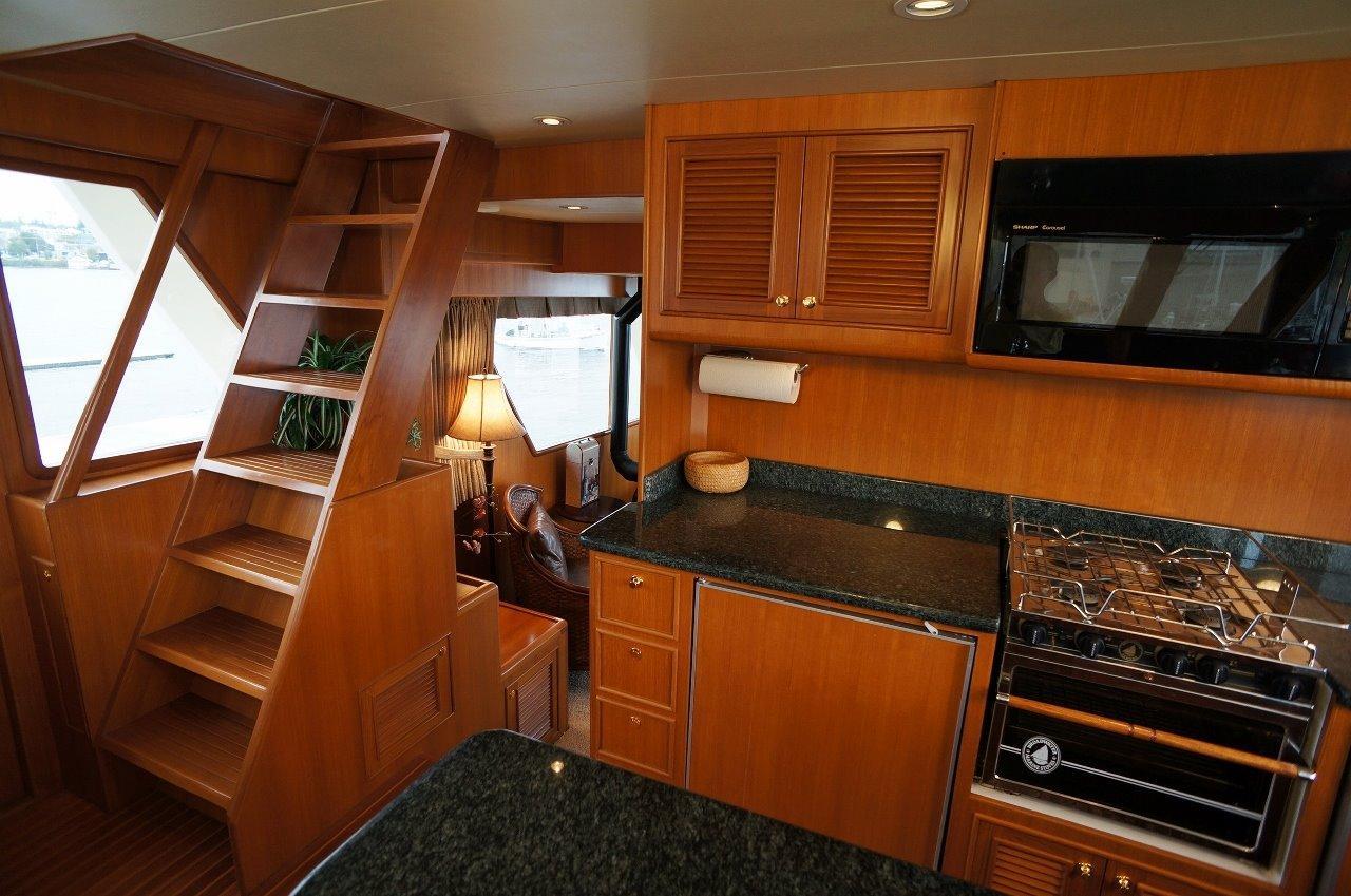 Interior of 2027 Legend Boats 630 Flybridge with wooden cabinetry and modern kitchen amenities.