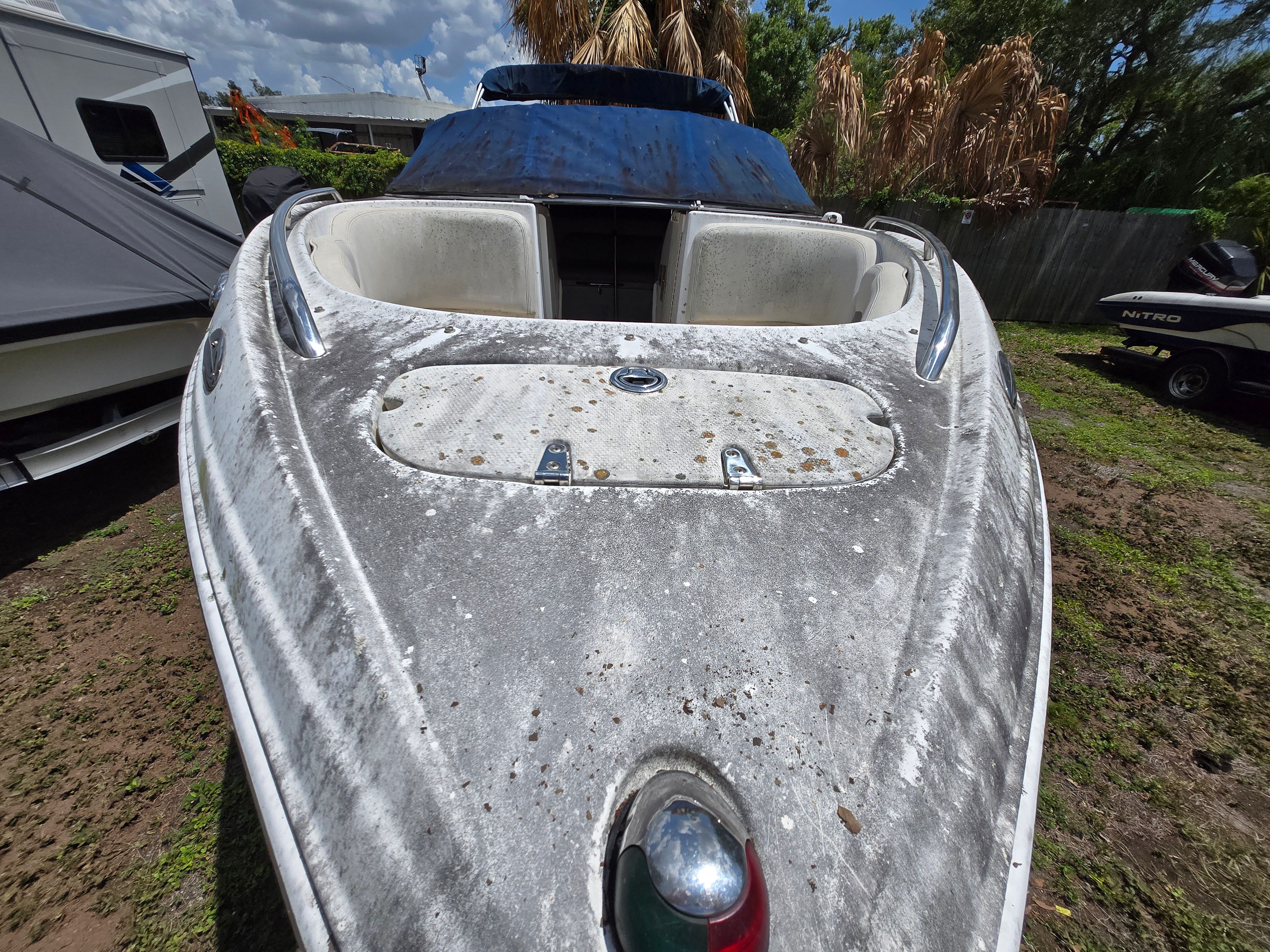 A 2006 Chaparral 220 SSi boat on grassy ground. It appears weathered with a blue cover.
