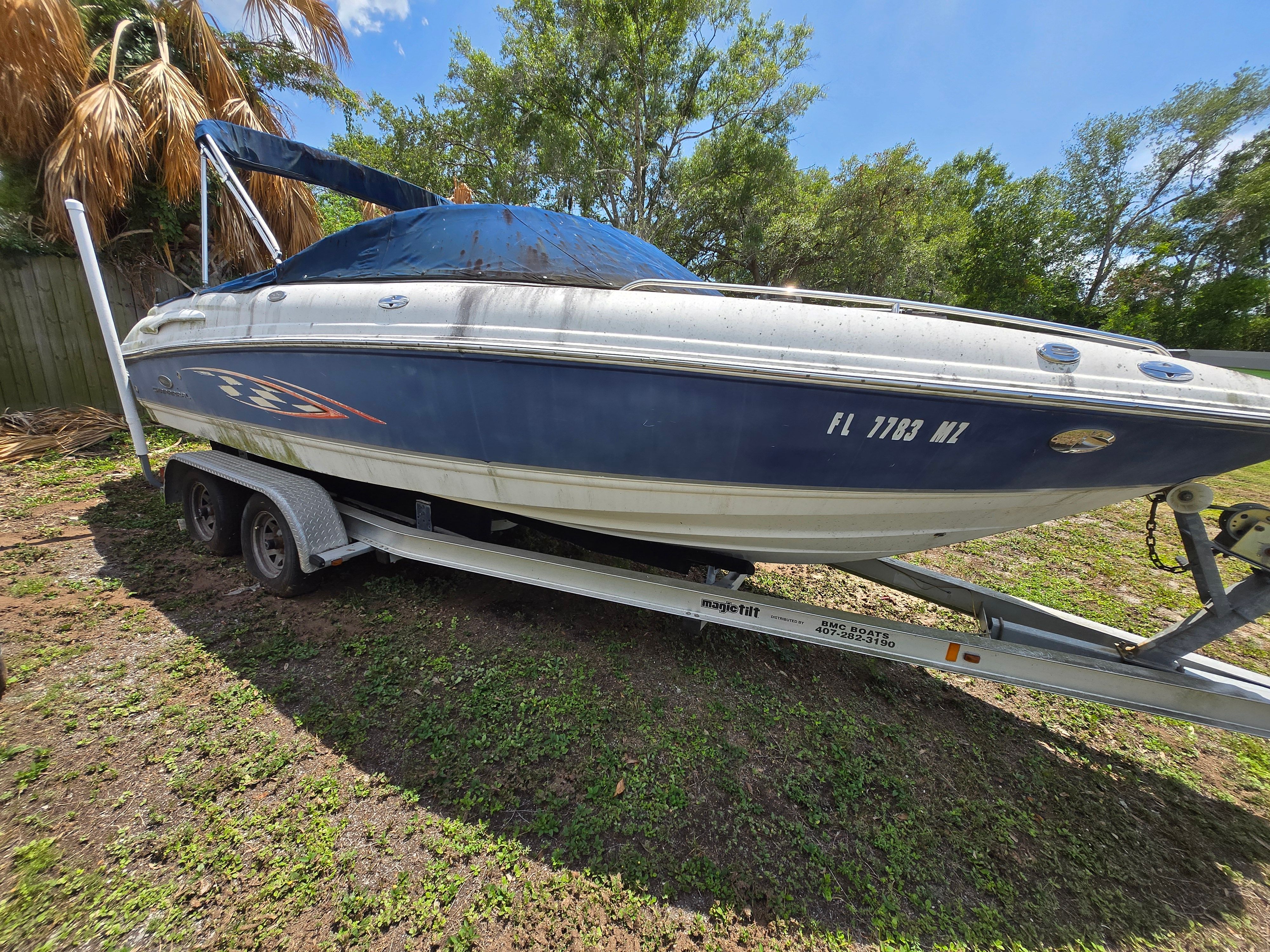A 2006 Chaparral 220 SSi boat on a trailer outdoors, surrounded by trees.