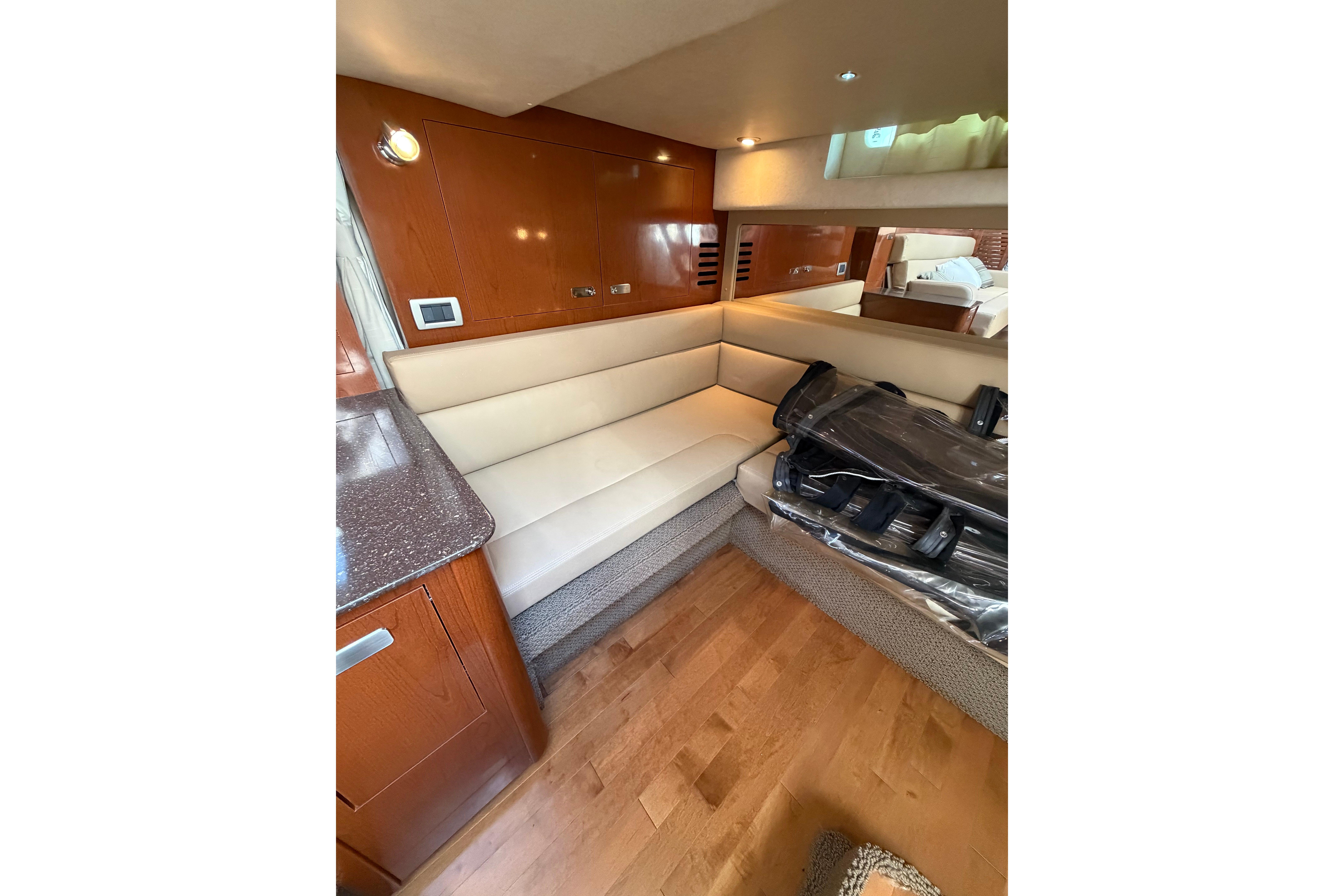 Interior of 2012 Sea Ray Sundancer 370 with beige seating and wooden cabinetry.