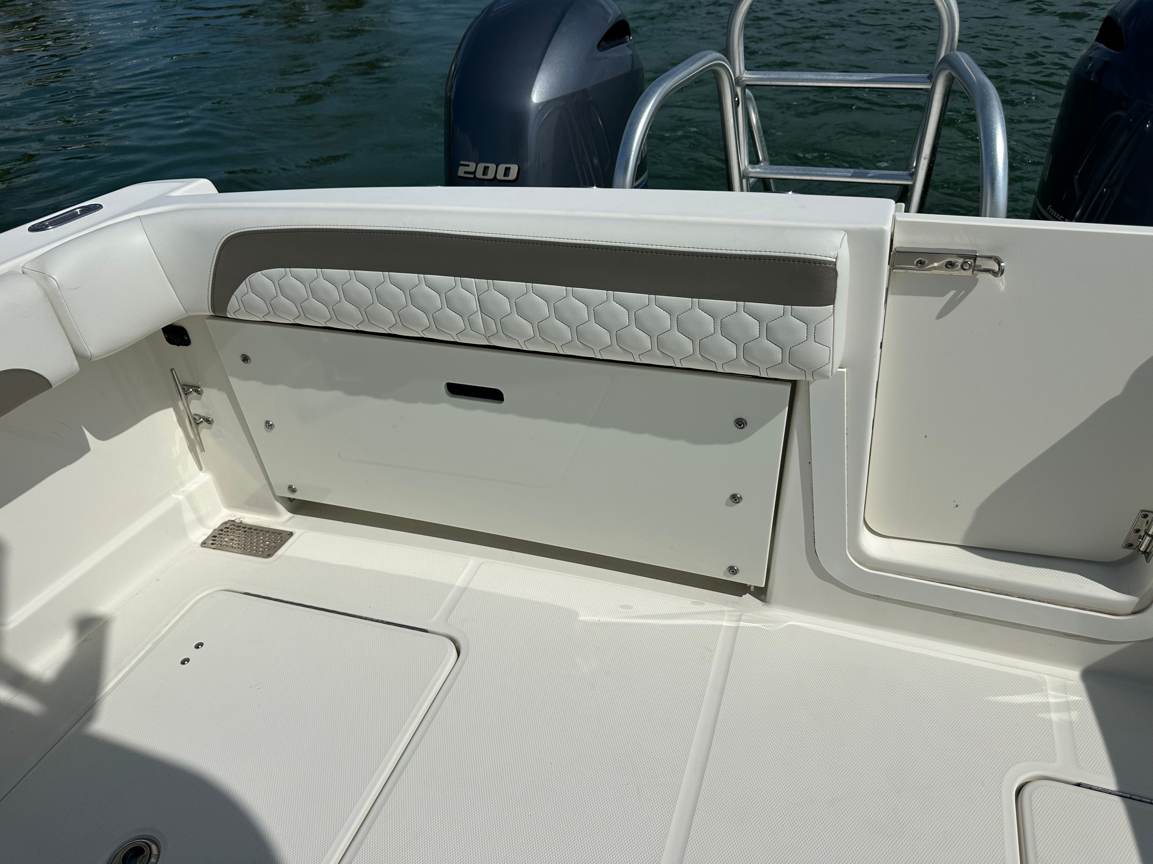 The image shows the stern of a boat with two outboard motors and a cushioned bench seat.