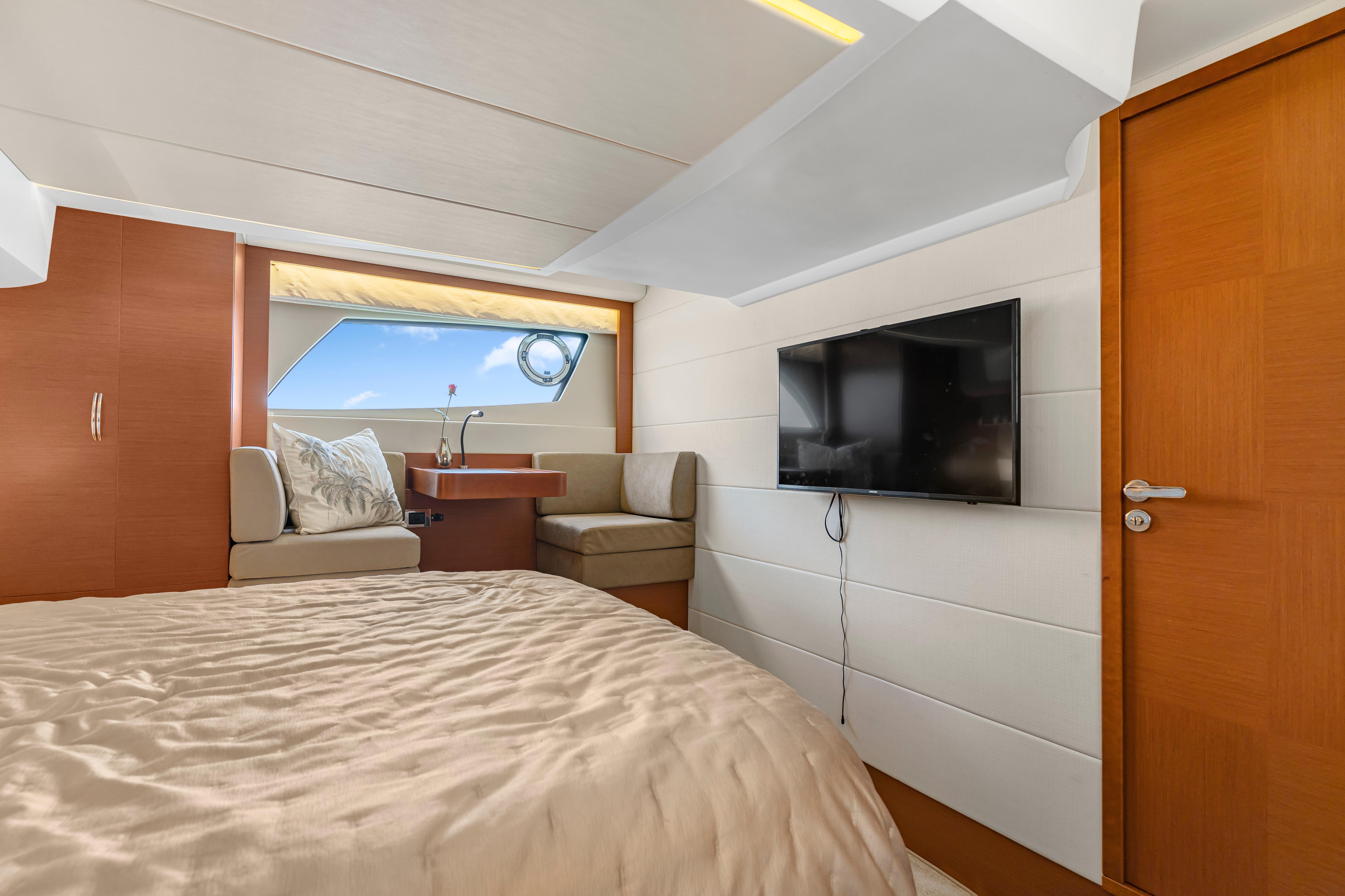 Luxurious cabin interior of 2017 Prestige 500 yacht with bed, seating, and TV.