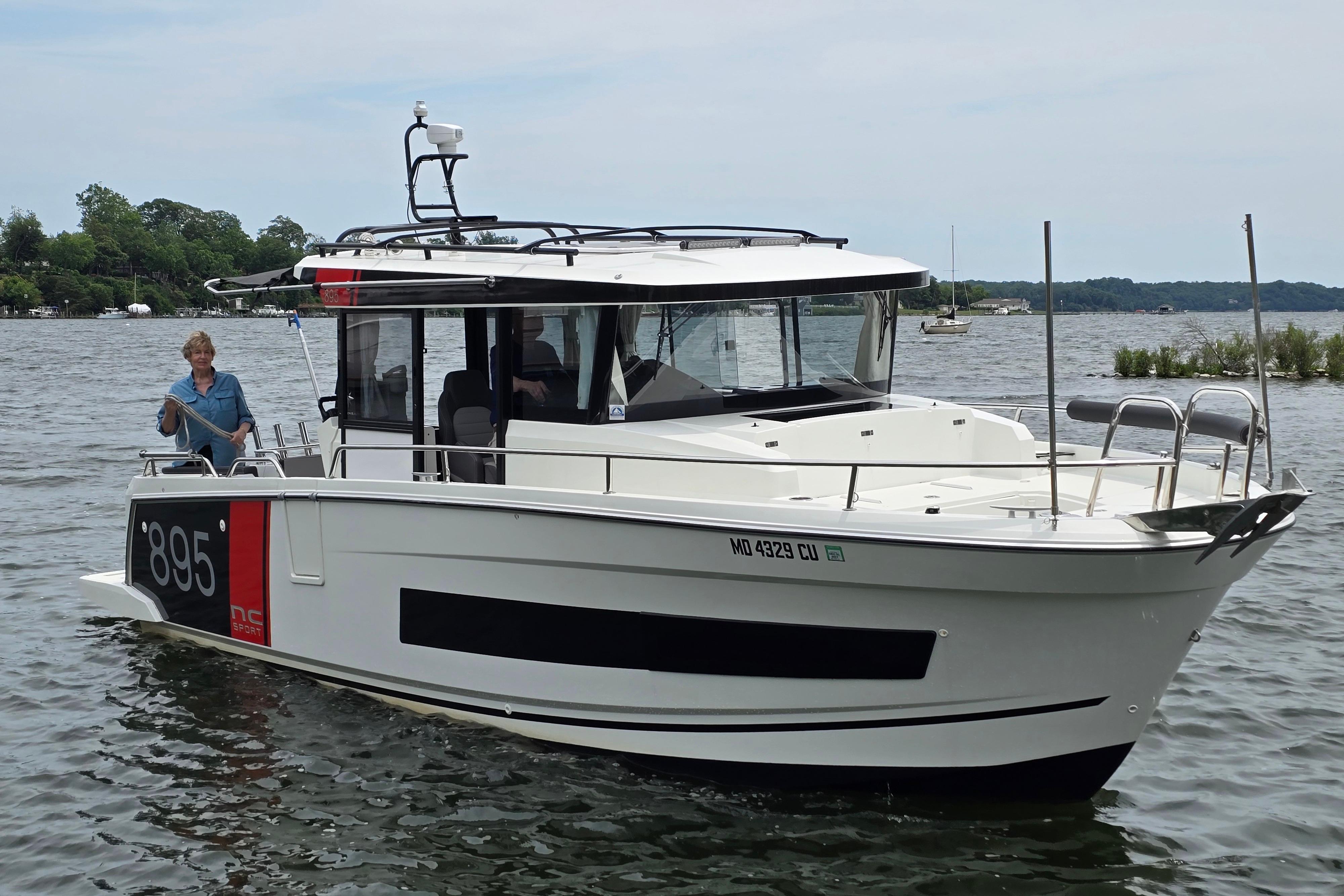 2023 Jeanneau NC Sport 895 boat cruising on a lake with a person onboard.
