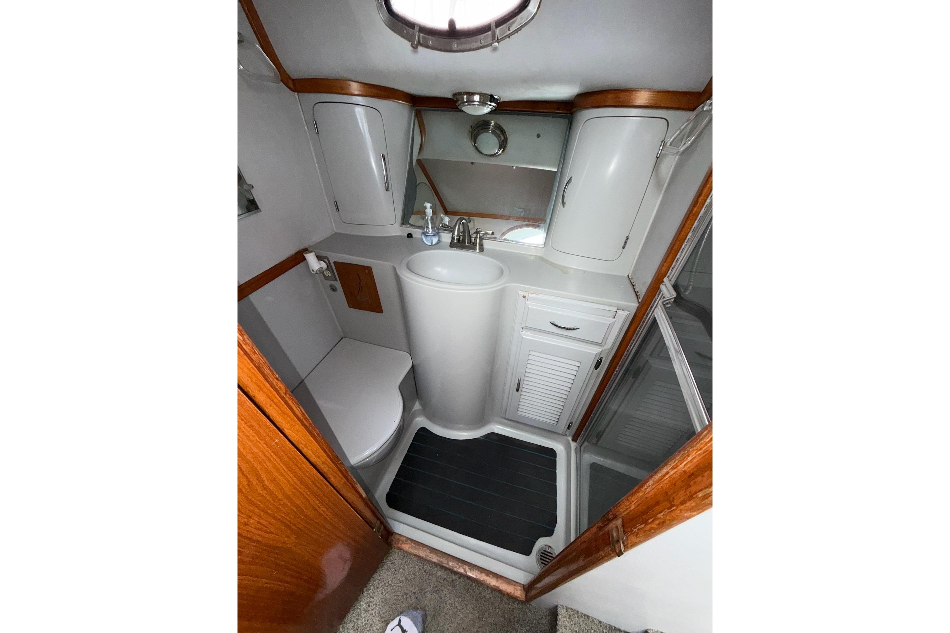Compact bathroom in a 1990 Mediterranean Sport Fish boat, featuring a sink, toilet, and storage cabinets.