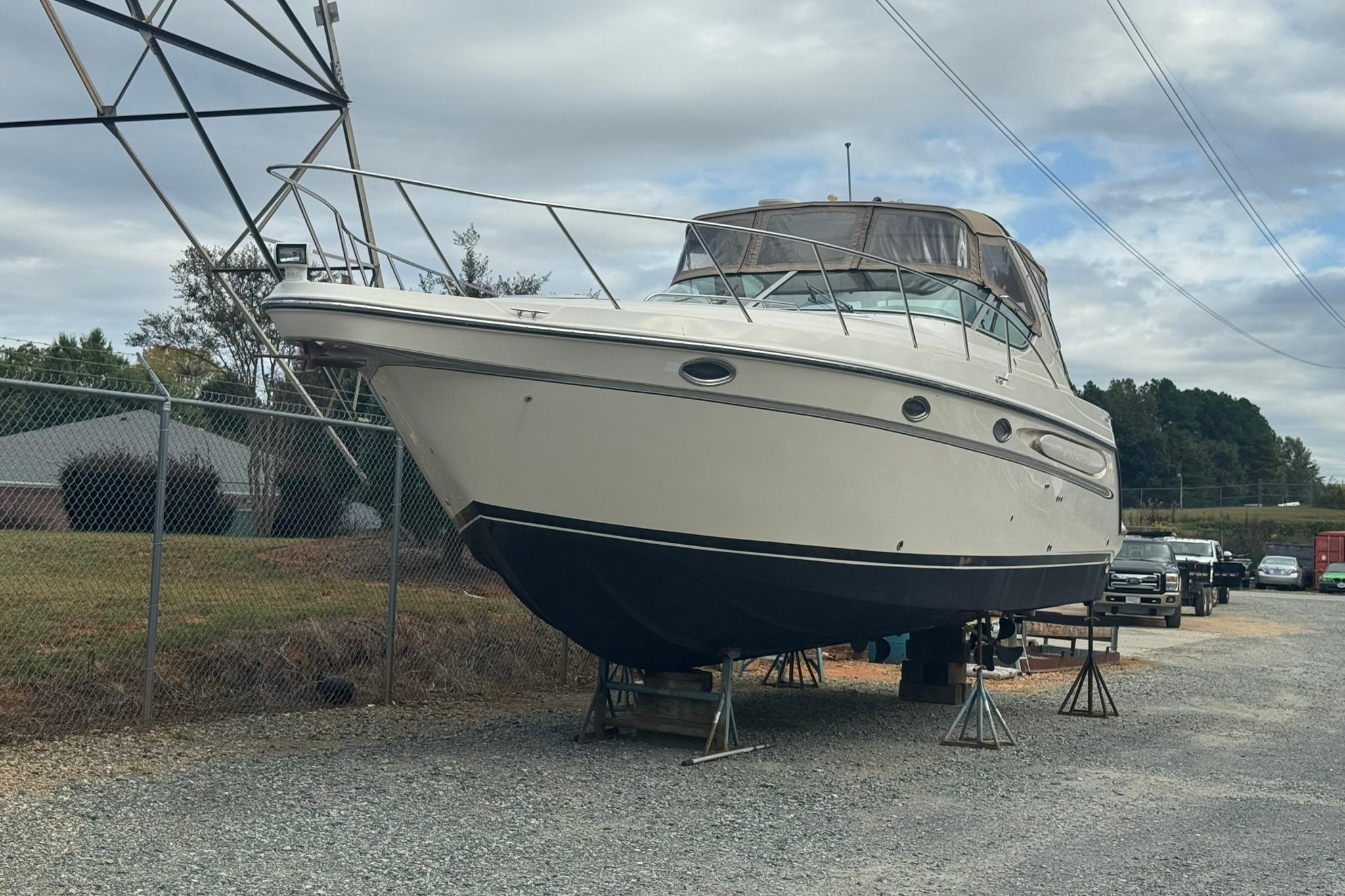 1998 Maxum 3700 SCR boat on stands in a storage yard.