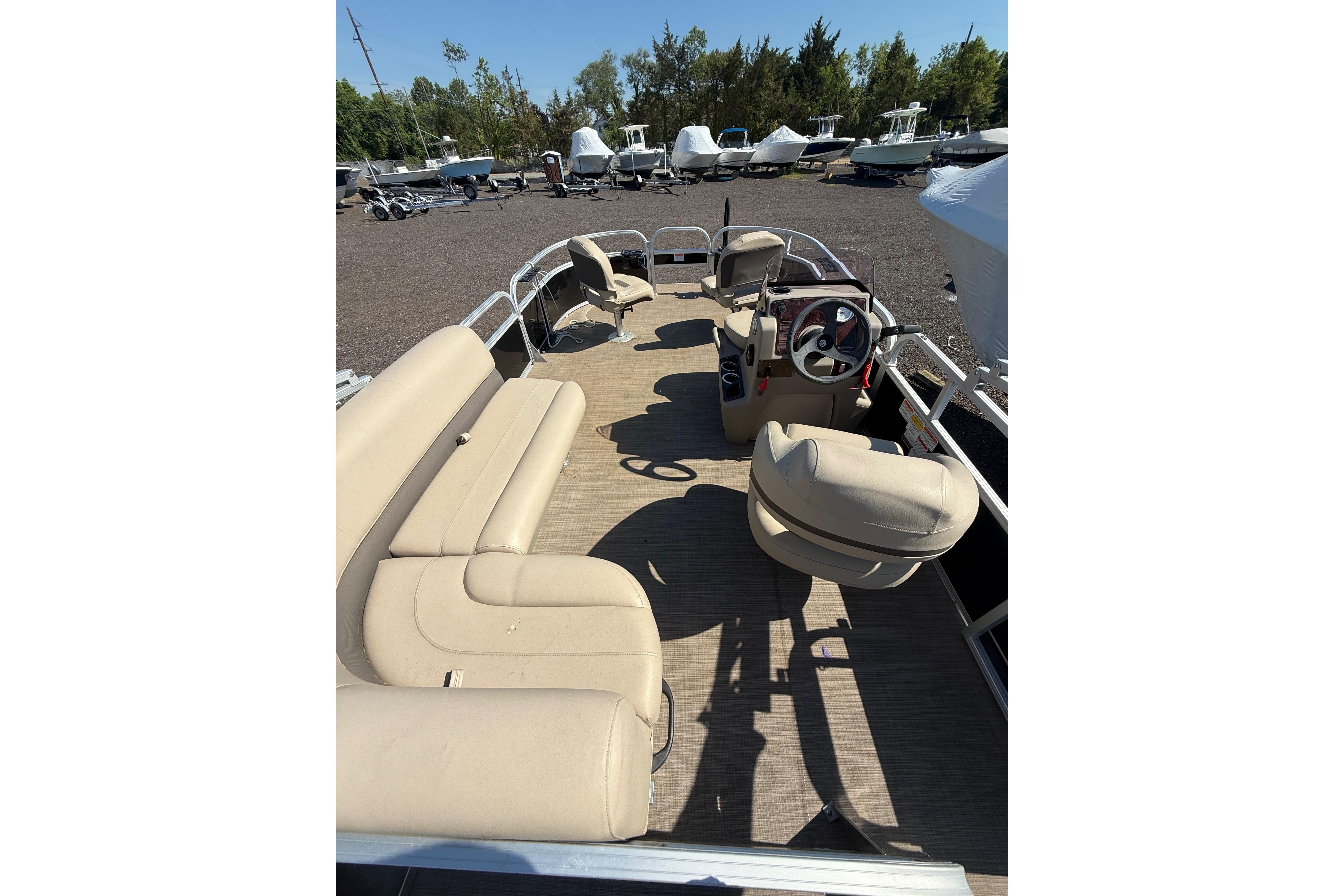 2021 Sun Tracker Bass Buggy 16 XL Select pontoon boat with beige seating and steering console.