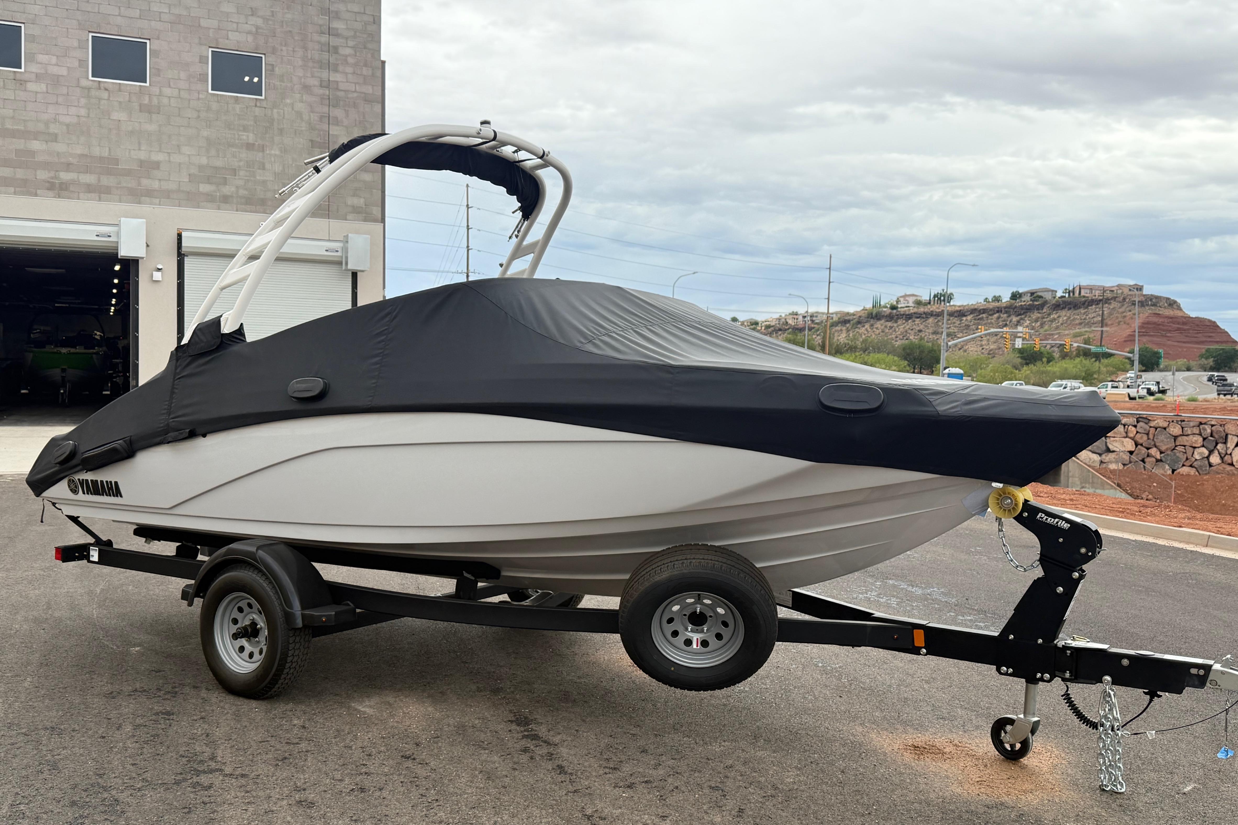 2025 Yamaha Boats 195S on trailer, covered, parked outside a building.
