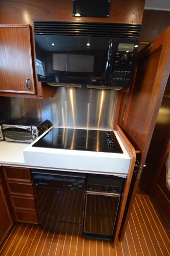 The 1980 Hatteras 53 Yacht Fisherman kitchen features a modern stove and microwave.
