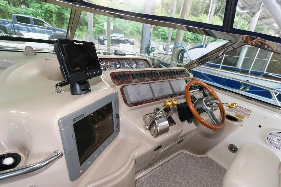 Cockpit of a 1999 Sea Ray Sundancer 400 with navigation equipment and wooden steering wheel.