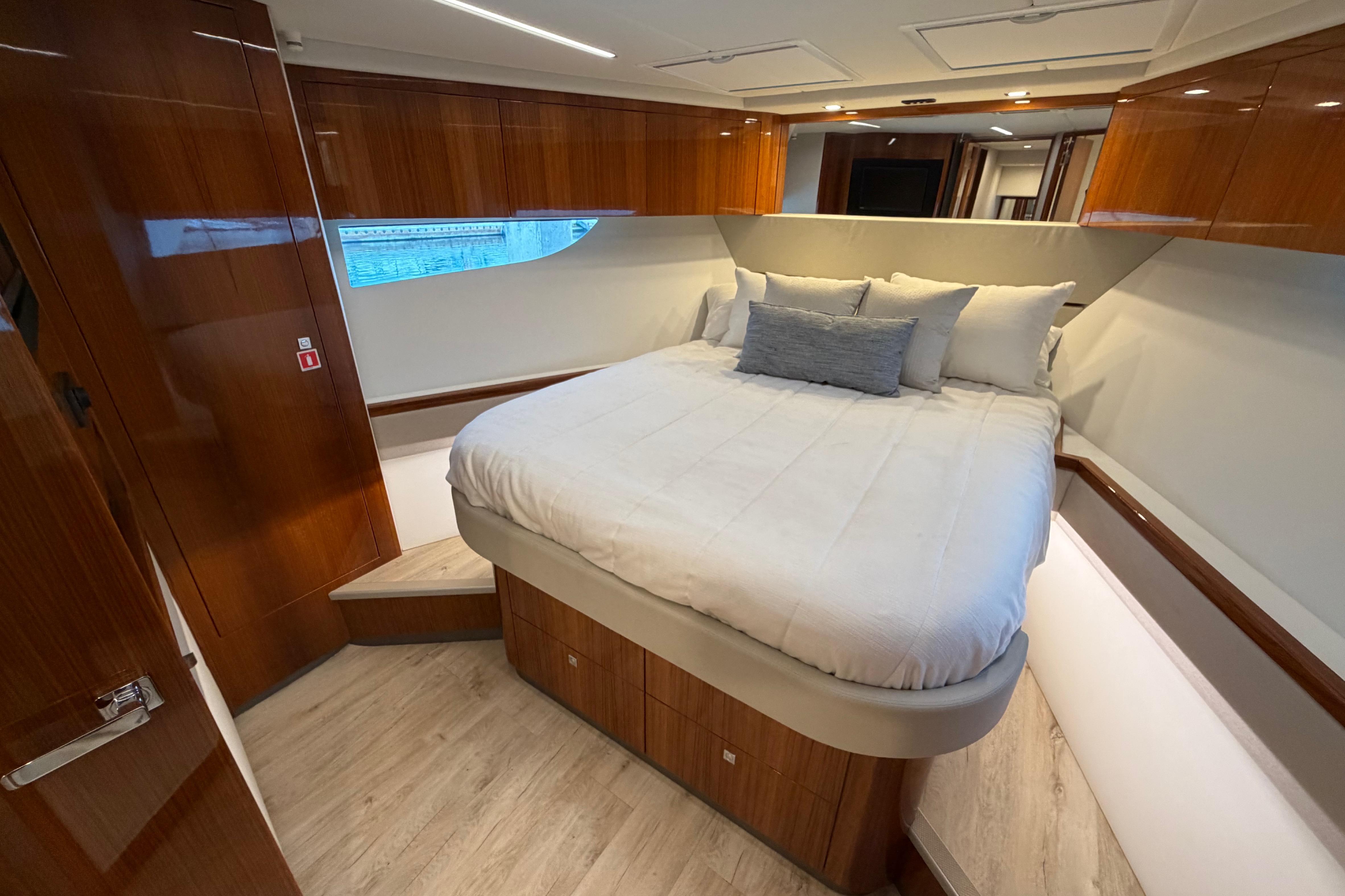 Luxurious bedroom interior of 2023 Riviera 645 SUV yacht with elegant wood finishes.