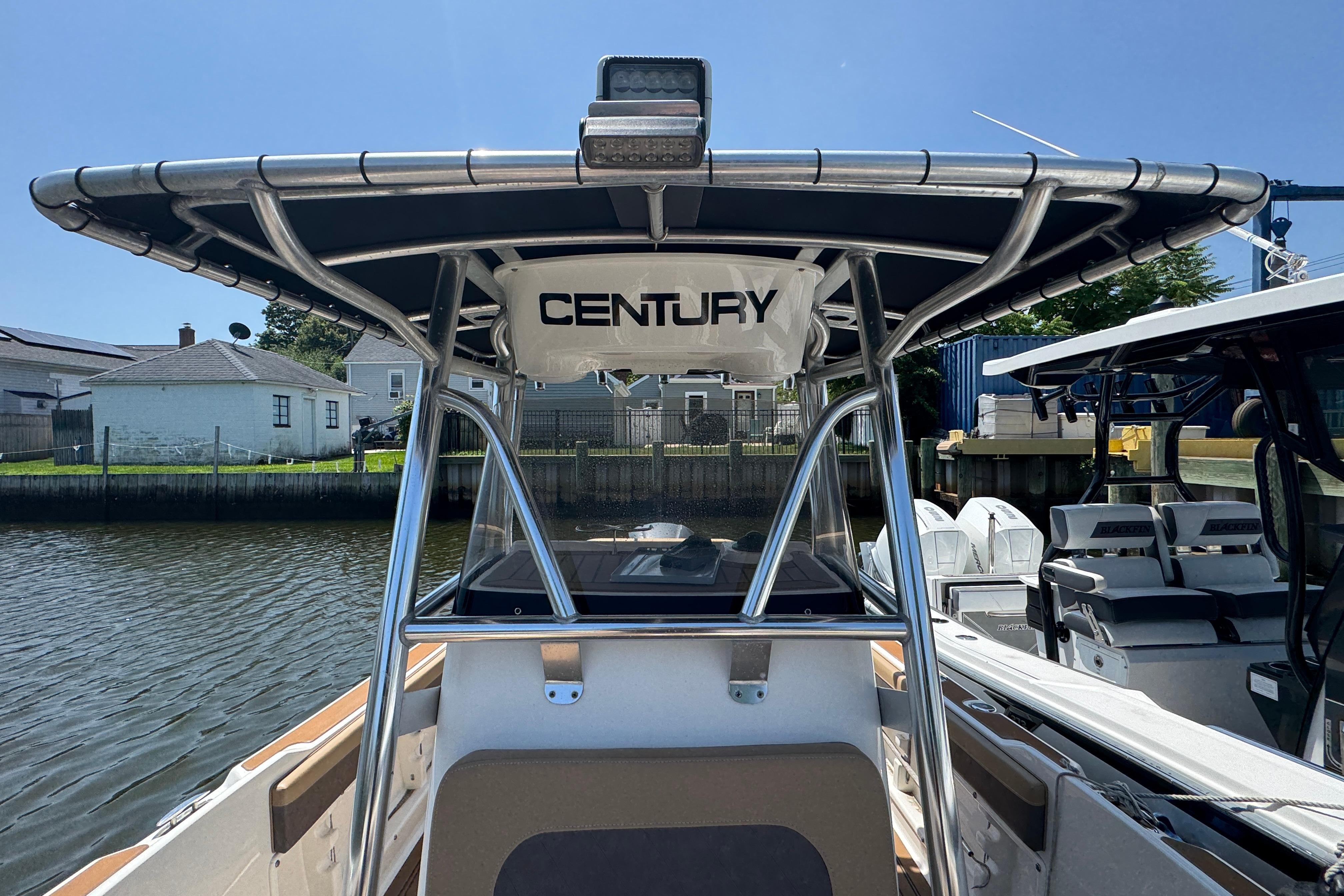 2014 Century 2301 Center Console boat docked, featuring sturdy T-top and sleek design.