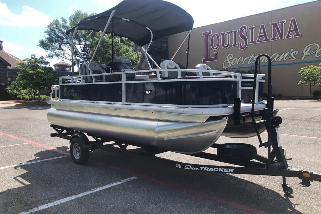 2026 Sun Tracker Bass Buggy 18 DLX pontoon boat on trailer, parked outdoors.