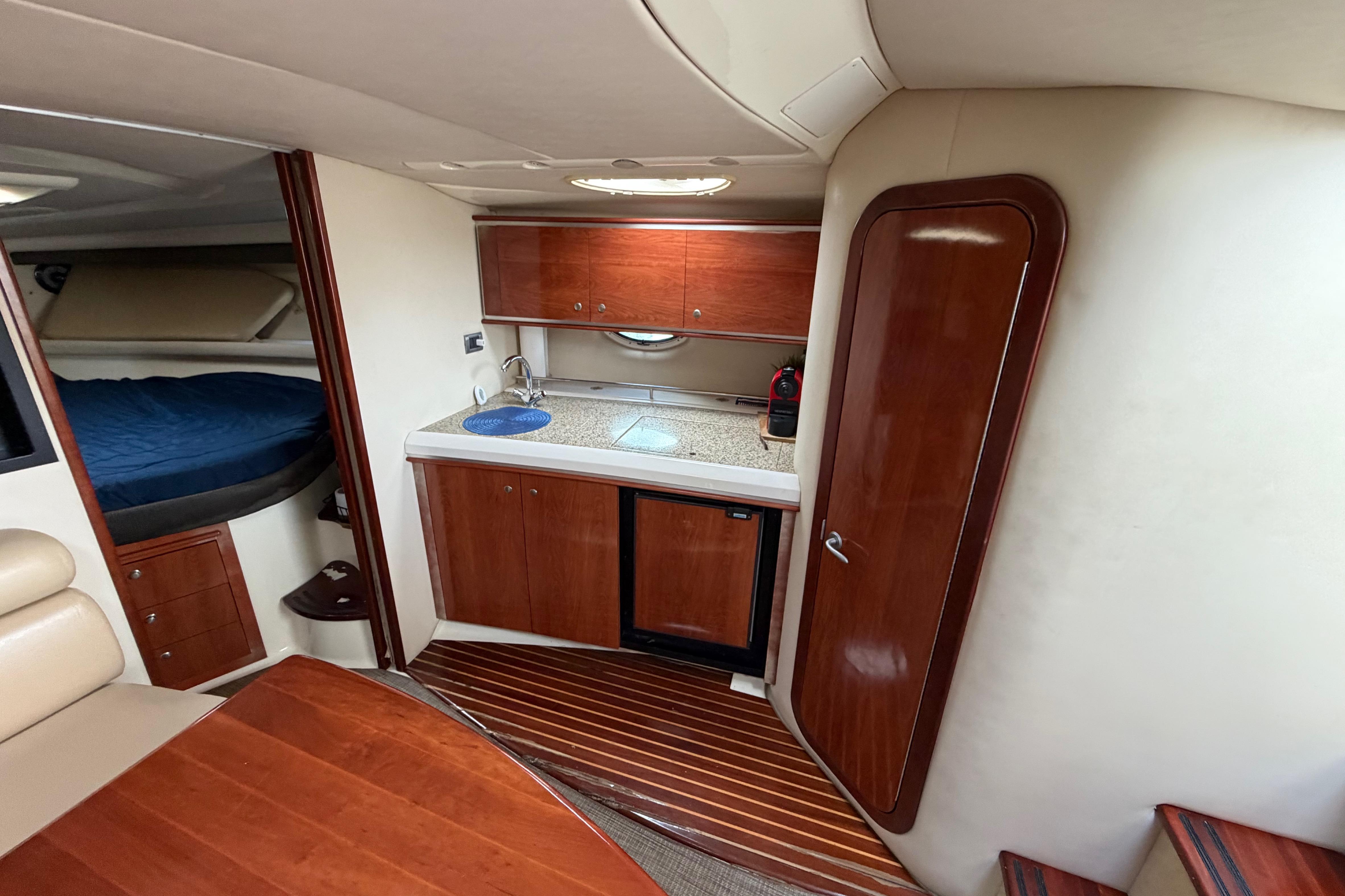 Interior of a 2007 Monterey 350 Sport Yacht featuring a compact kitchen and cozy sleeping area.