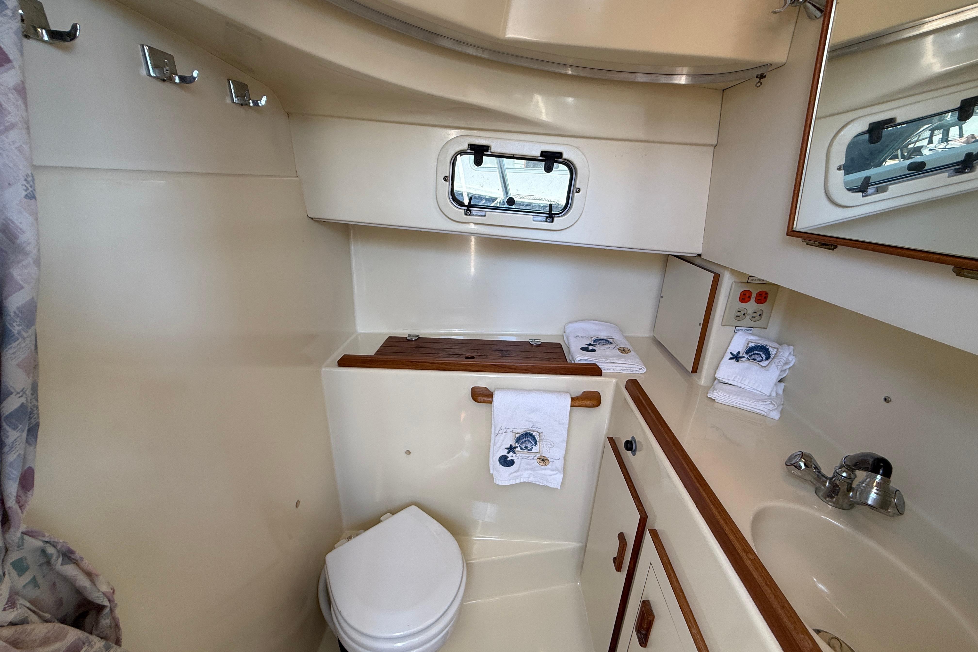 1994 Camano Troll boat bathroom with sink, toilet, and porthole window.