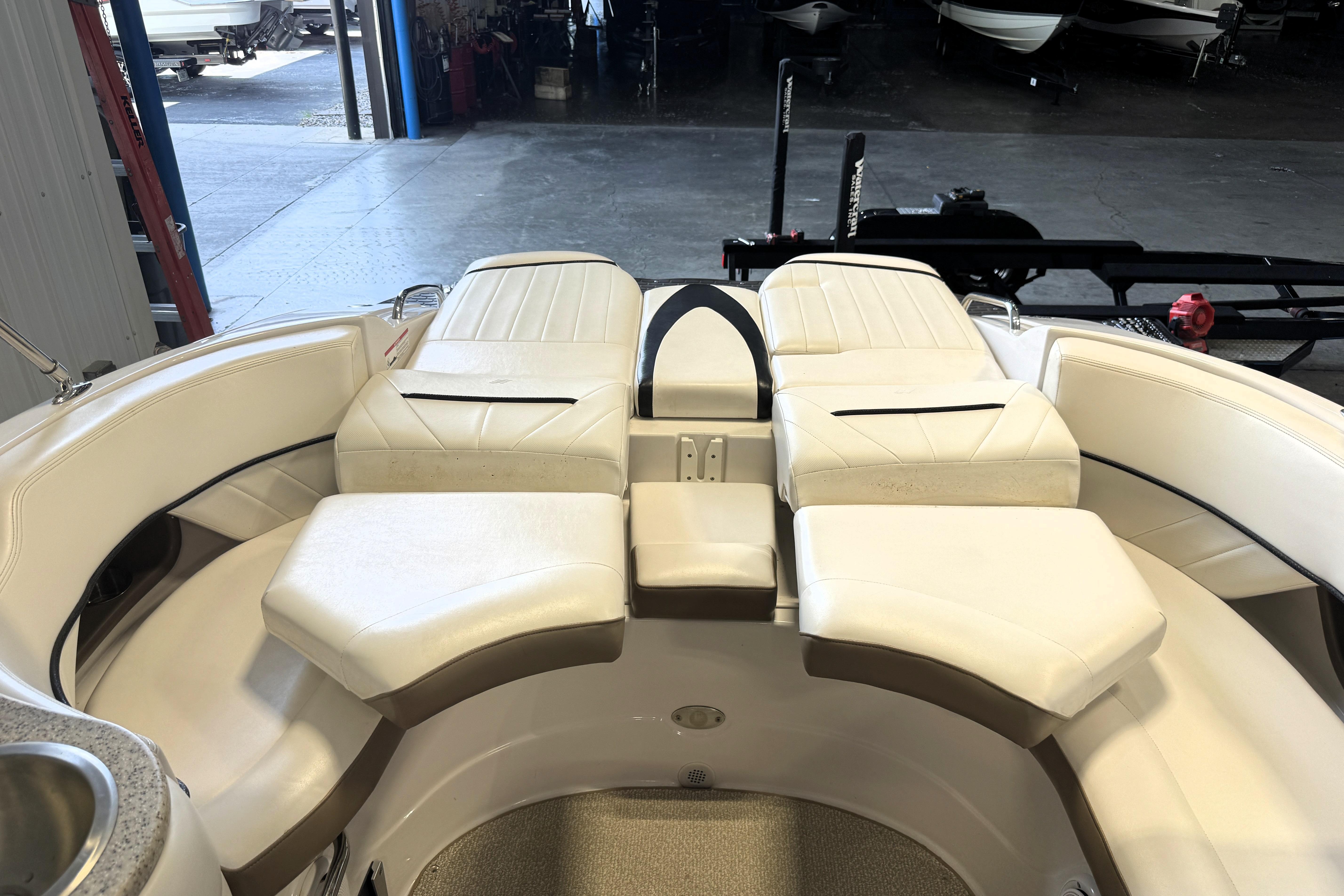 2008 Four Winns H240 boat interior with white cushioned seating in a garage setting.