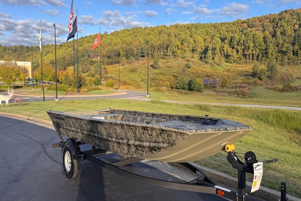 2026 Tracker Grizzly 1754 Utility boat on trailer, scenic background with flags and trees.