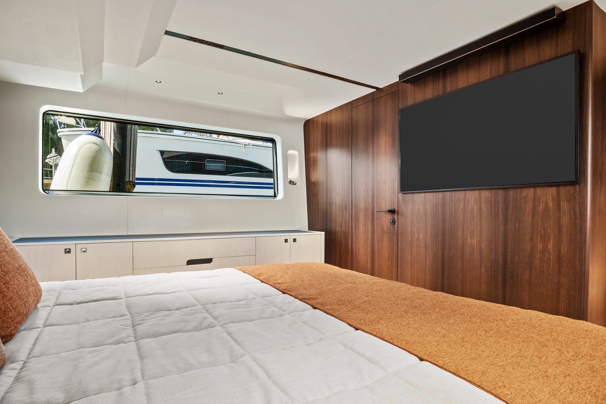 Luxurious 2023 Astondoa AS5 yacht bedroom with modern wood paneling and large window.