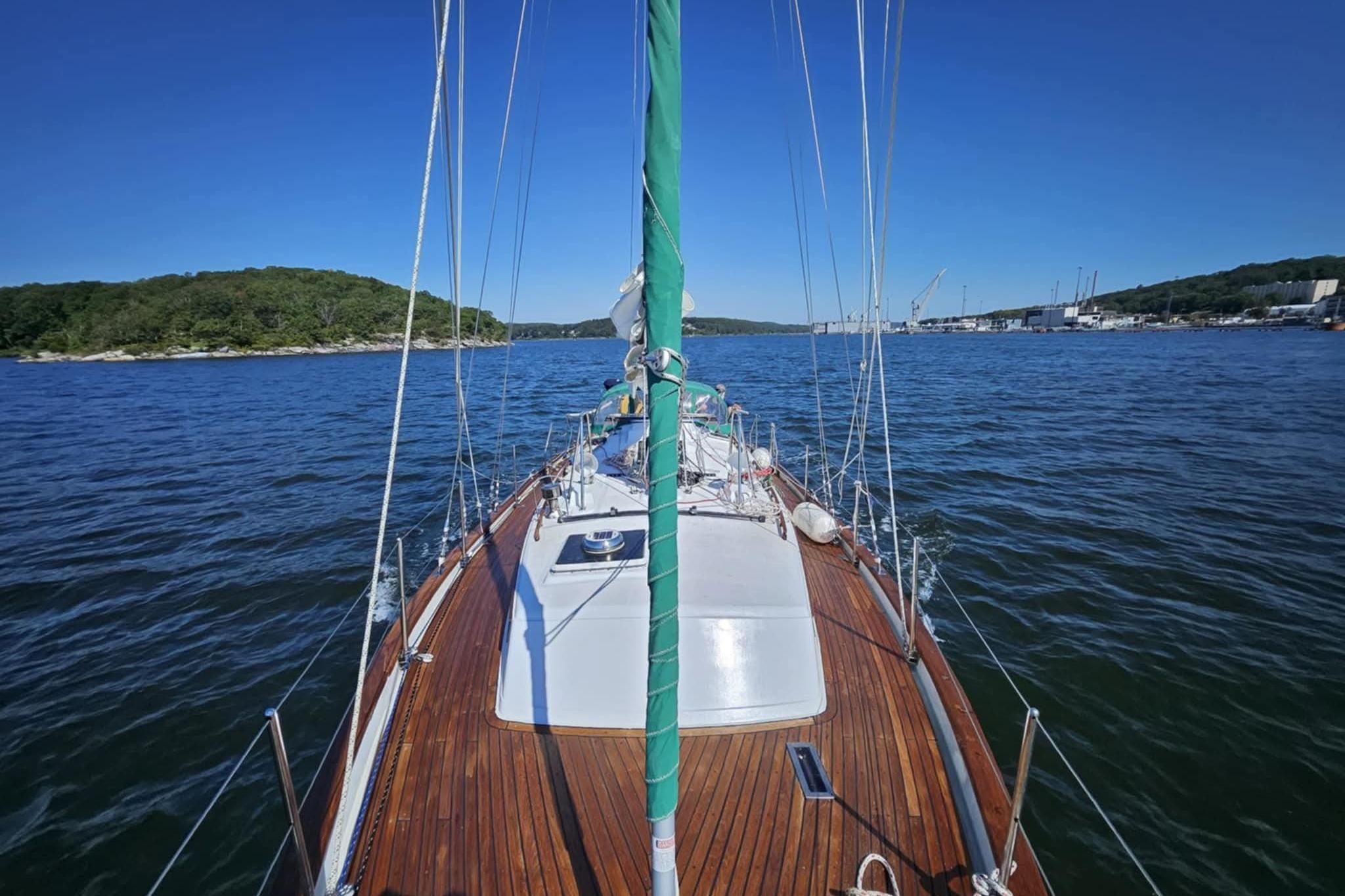 1986 Crealock 40 sailboat on calm waters with scenic shoreline view.