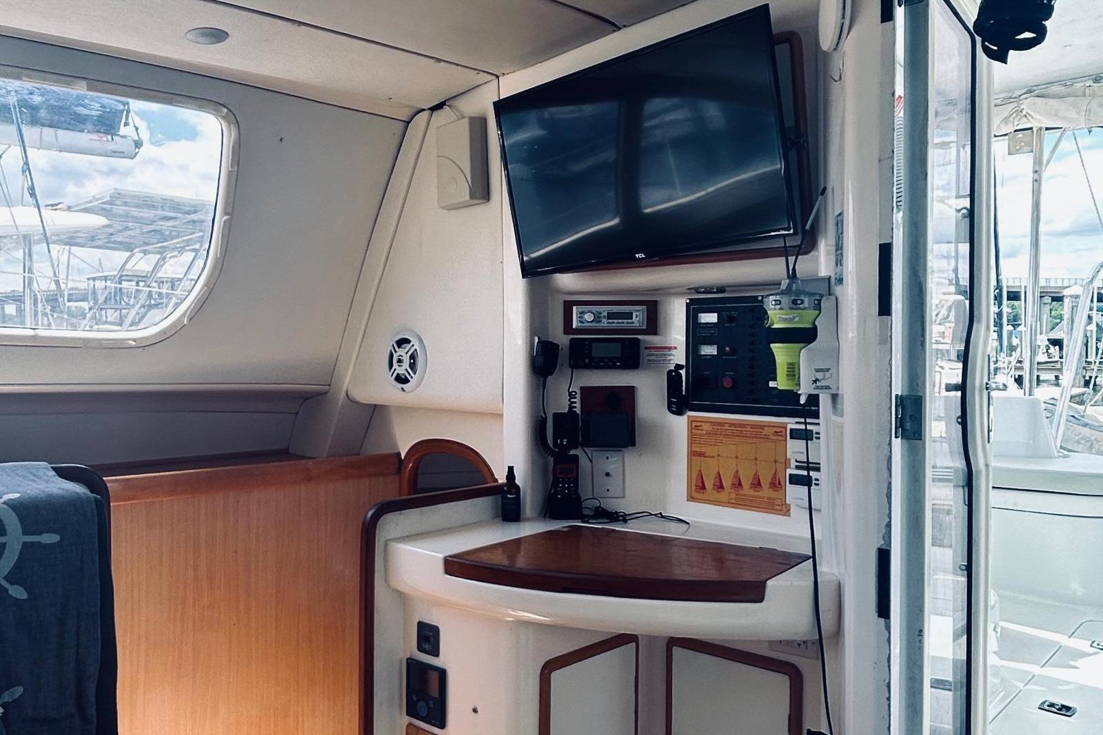 Interior of a 2001 Robertson & Caine Leopard yacht with navigation equipment and a mounted TV.