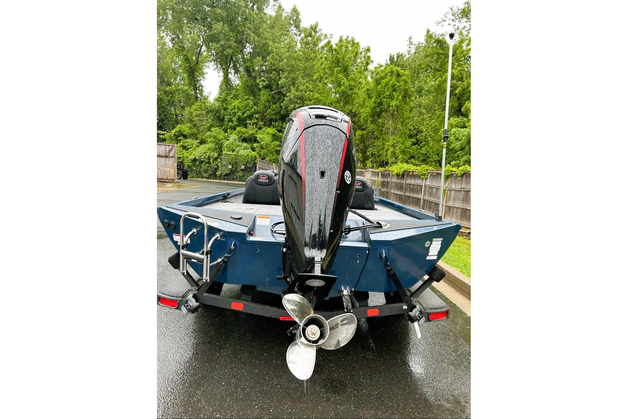 2026 Ranger RT188P boat with outboard motor on a trailer, parked on wet pavement.