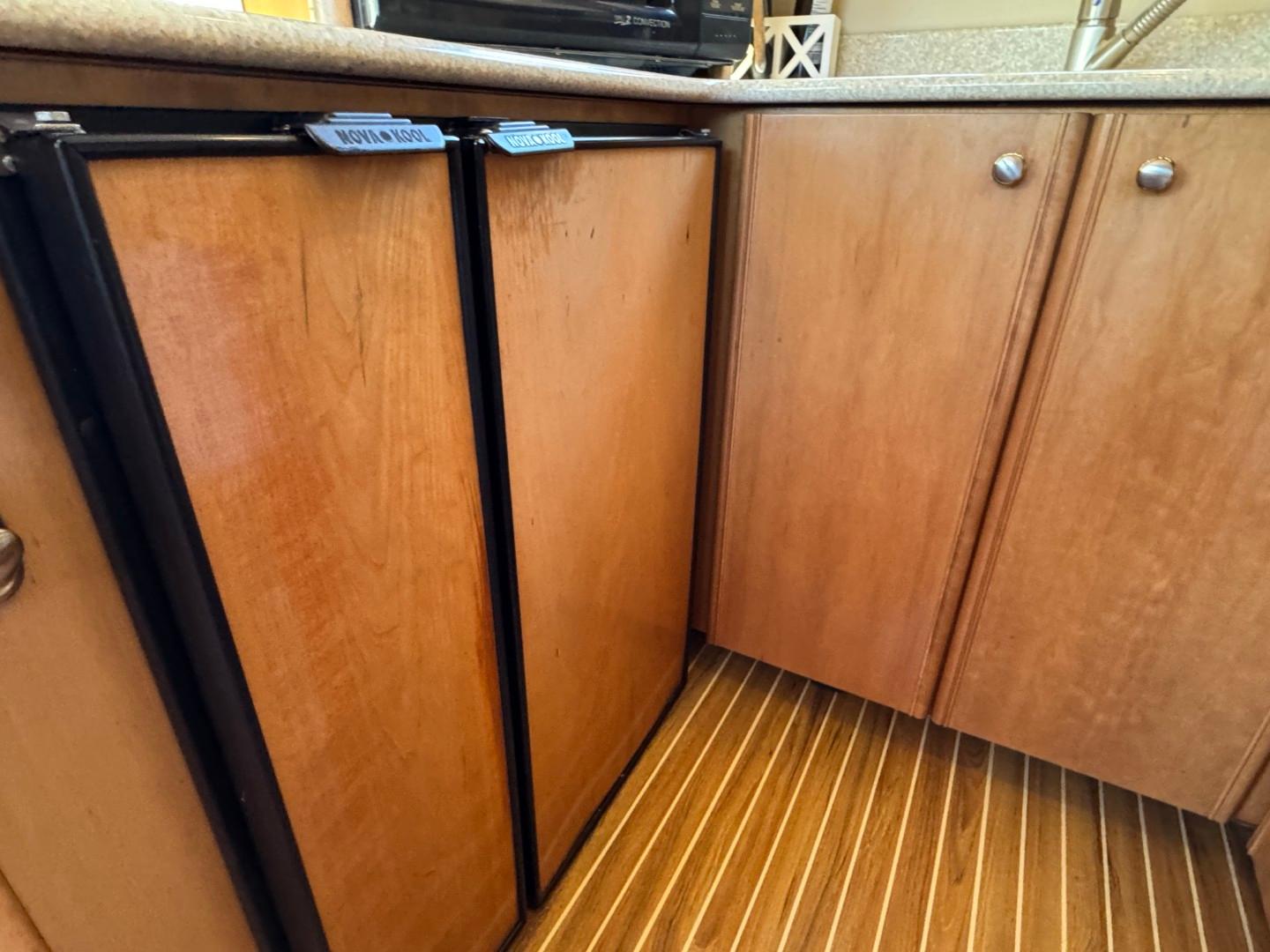 Wooden cabinetry and flooring in a 2003 Meridian 381 Sedan yacht kitchen.