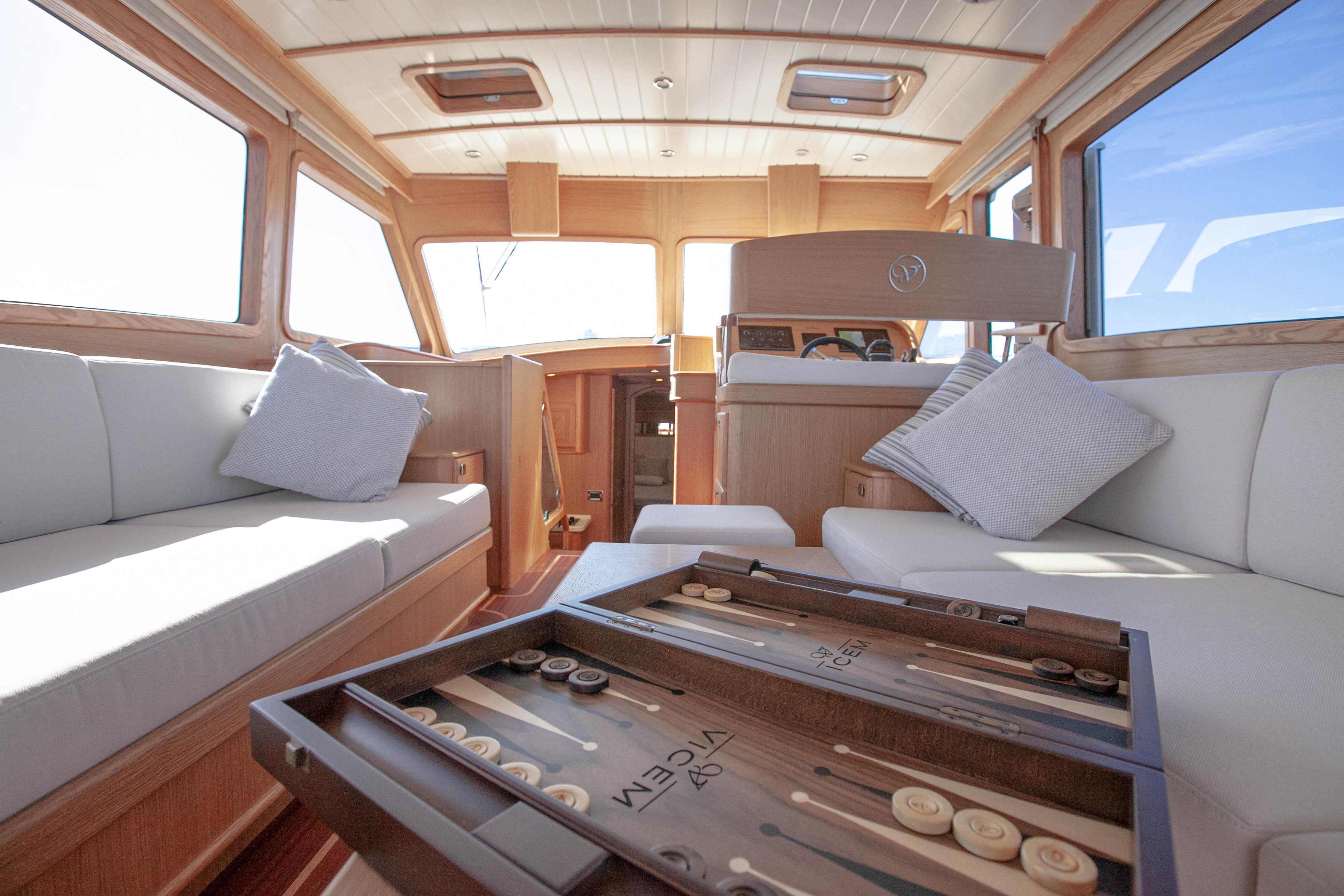 Luxurious interior of 2023 Vicem 55 yacht with elegant seating and backgammon set.