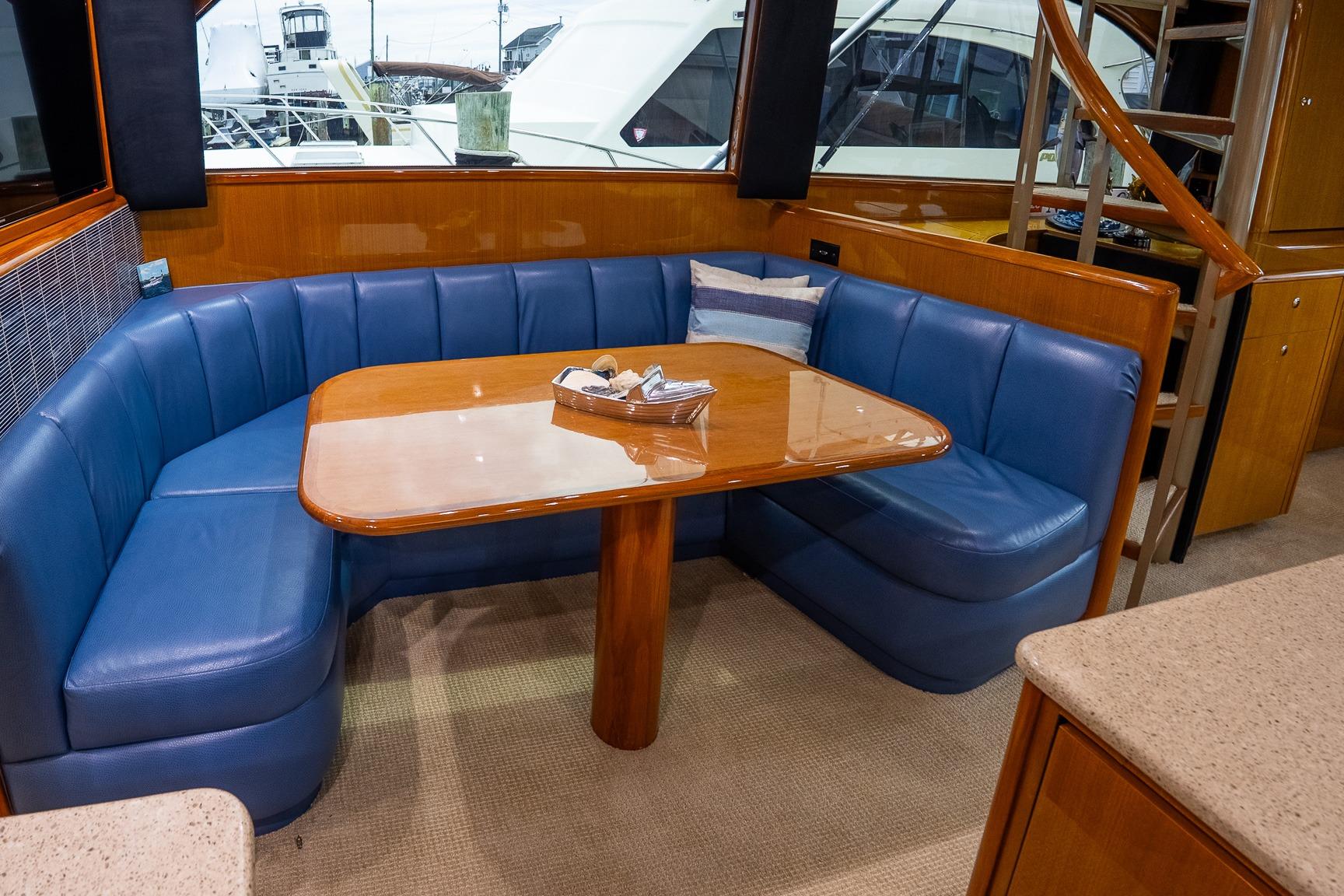 Luxurious interior of 2002 Viking 61 Enclosed Bridge yacht with blue seating and wooden table.
