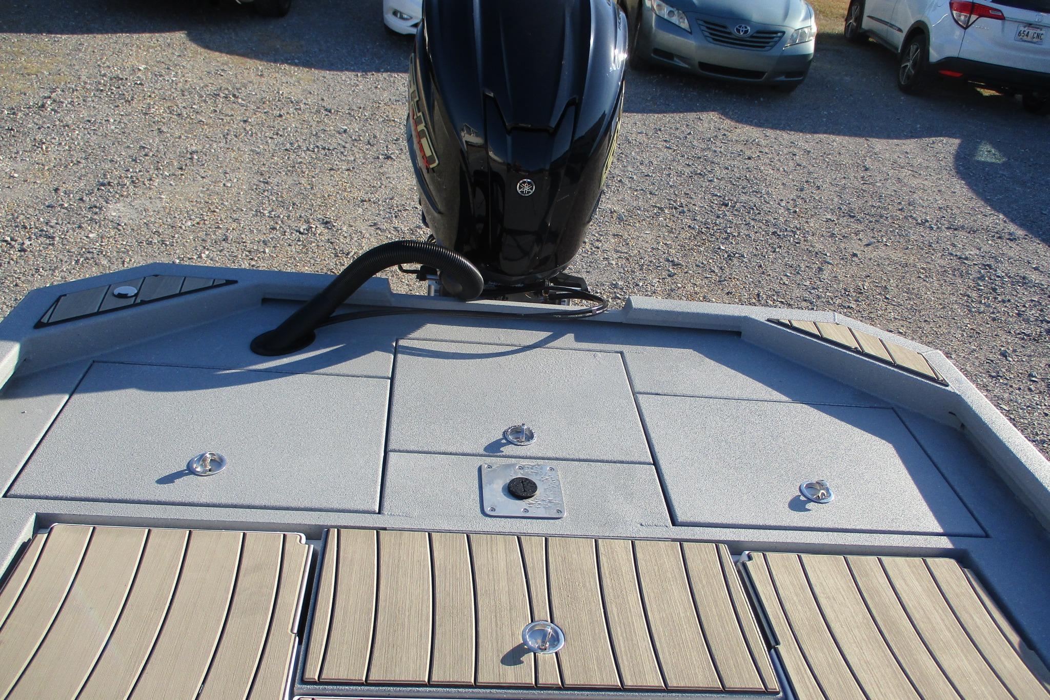 2026 Vexus ACX2210 boat deck with motor, parked on gravel lot.