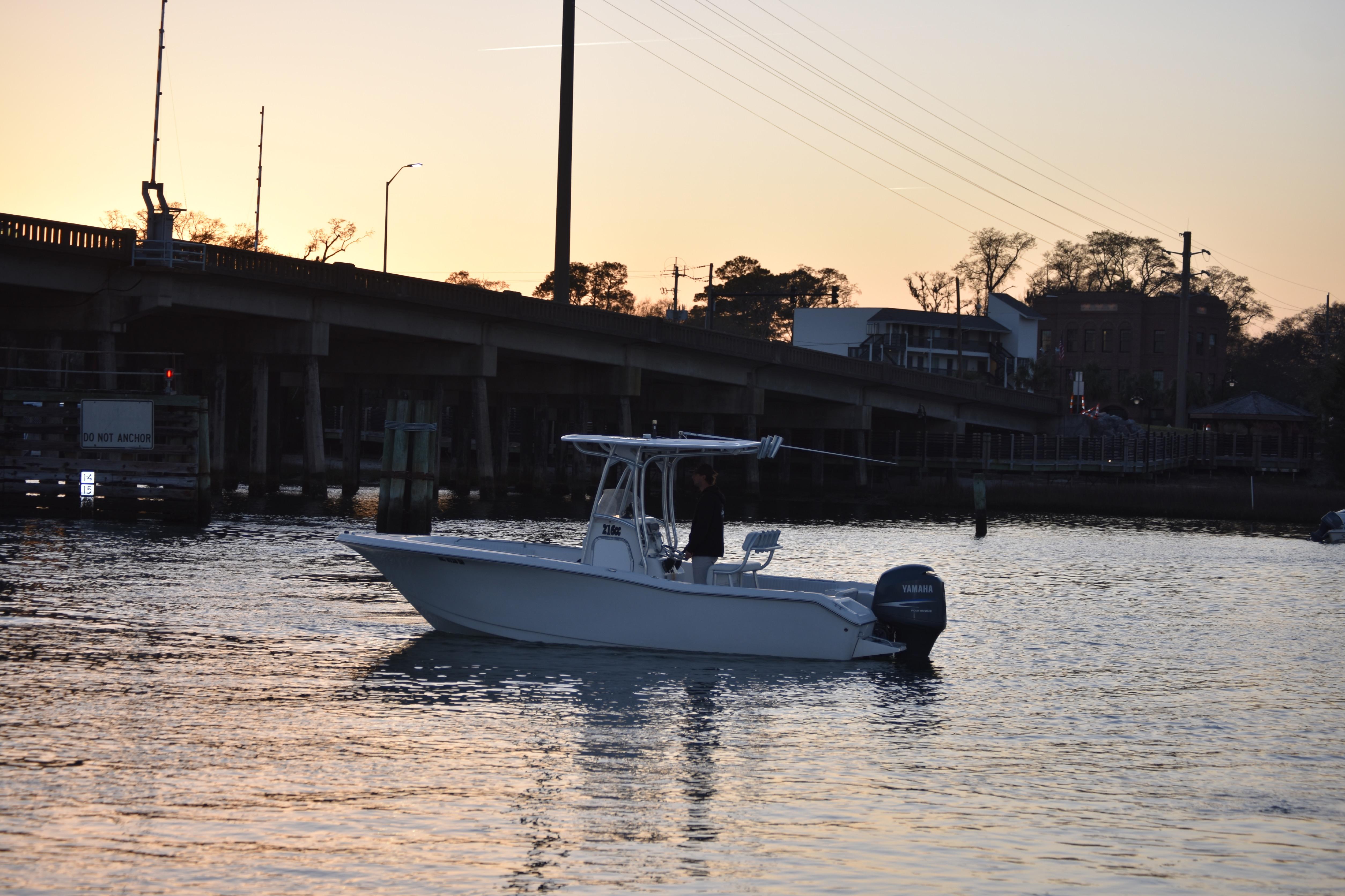 2007 Tidewater 216 CC Adventure boat on water at sunset near a bridge.