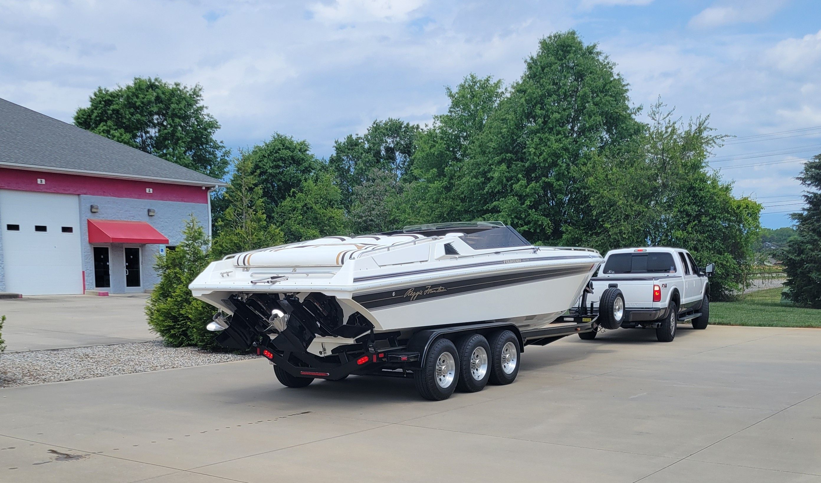 1992 Fountain Fever boat on trailer, parked near a building with trees in the background.