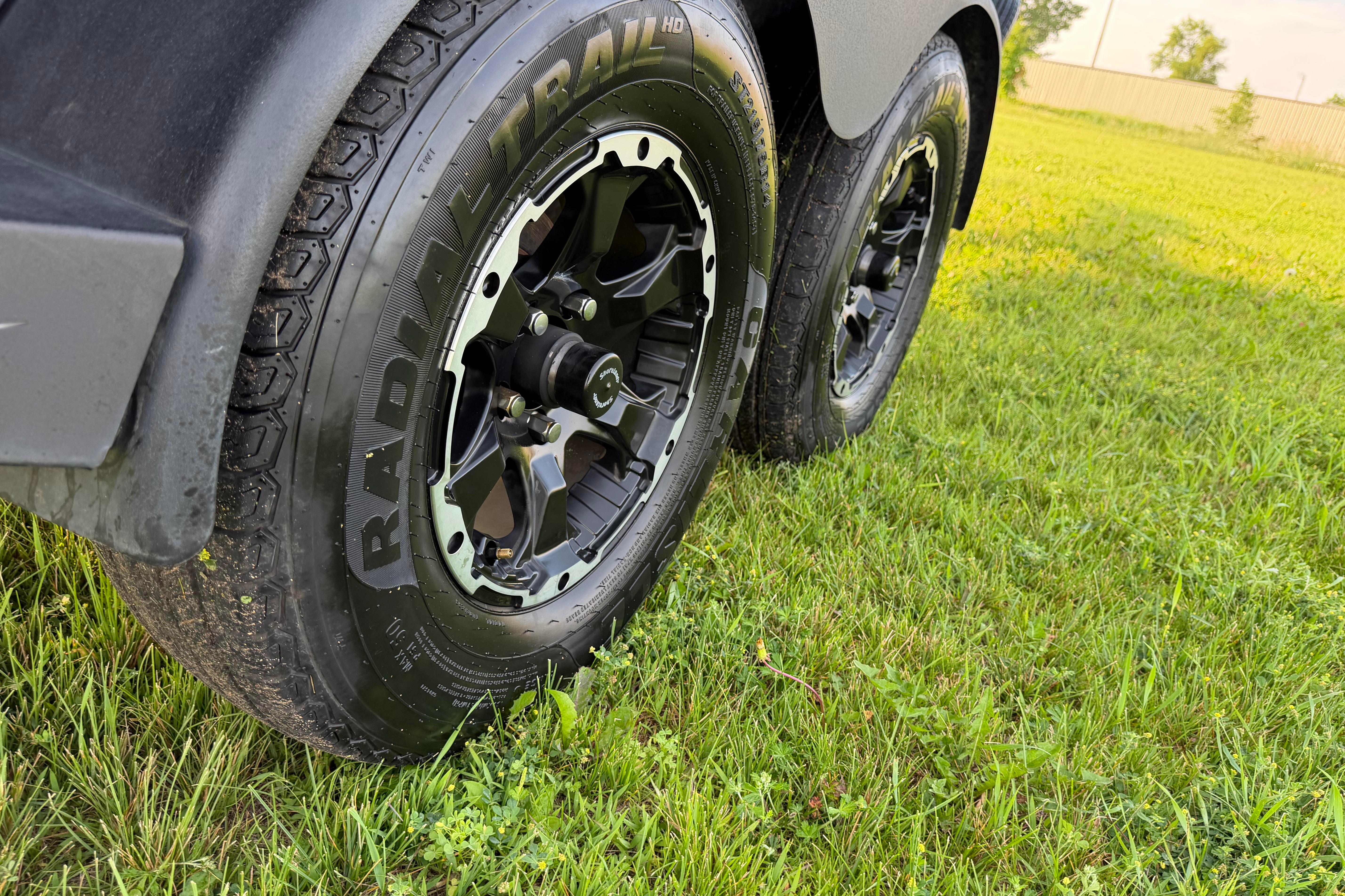 Trailer wheels of a 2019 Alumacraft Trophy 205 on grassy field.