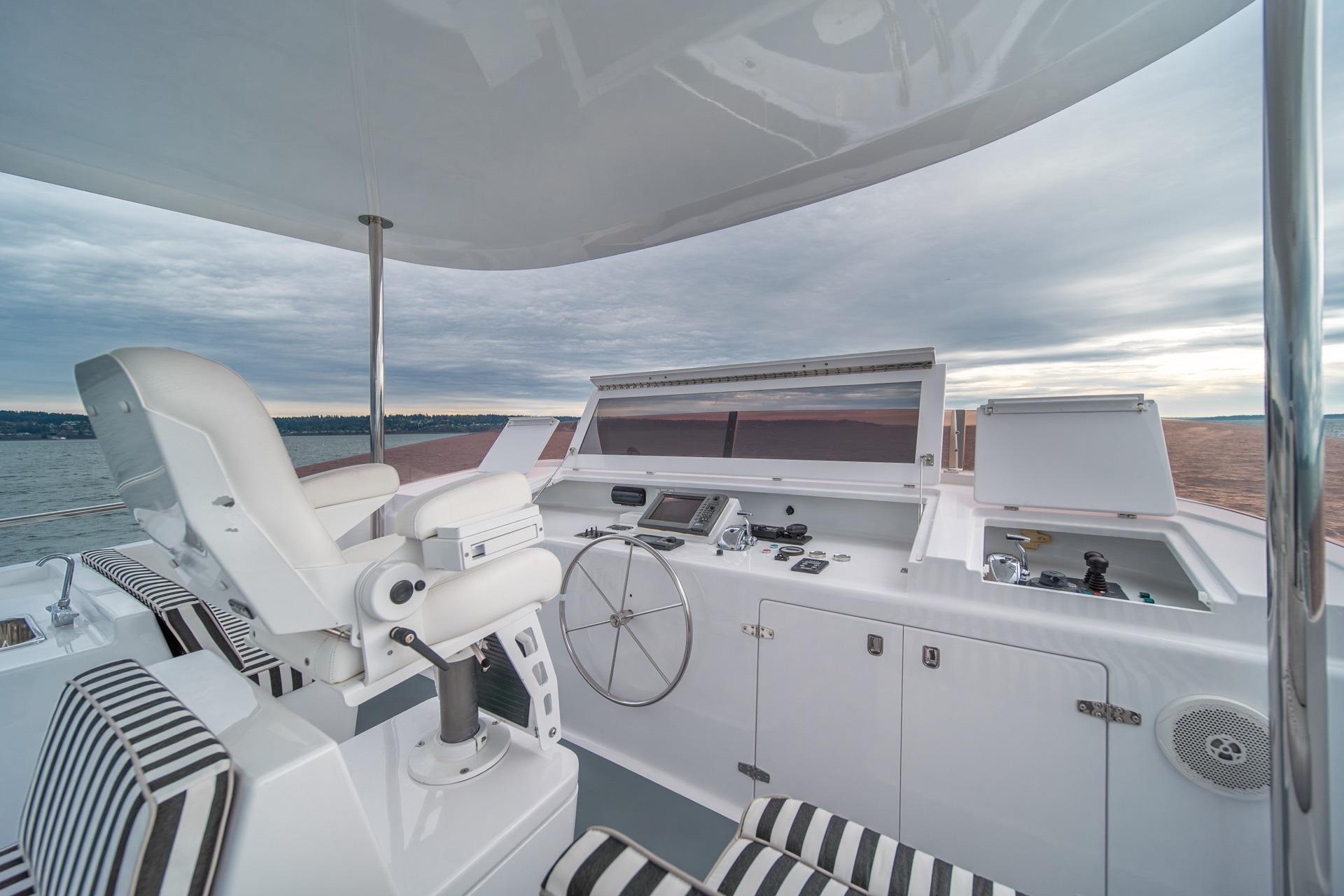 Luxurious helm of 2004 Northern Marine 80' Tri-Deck Expedition yacht with striped seating.