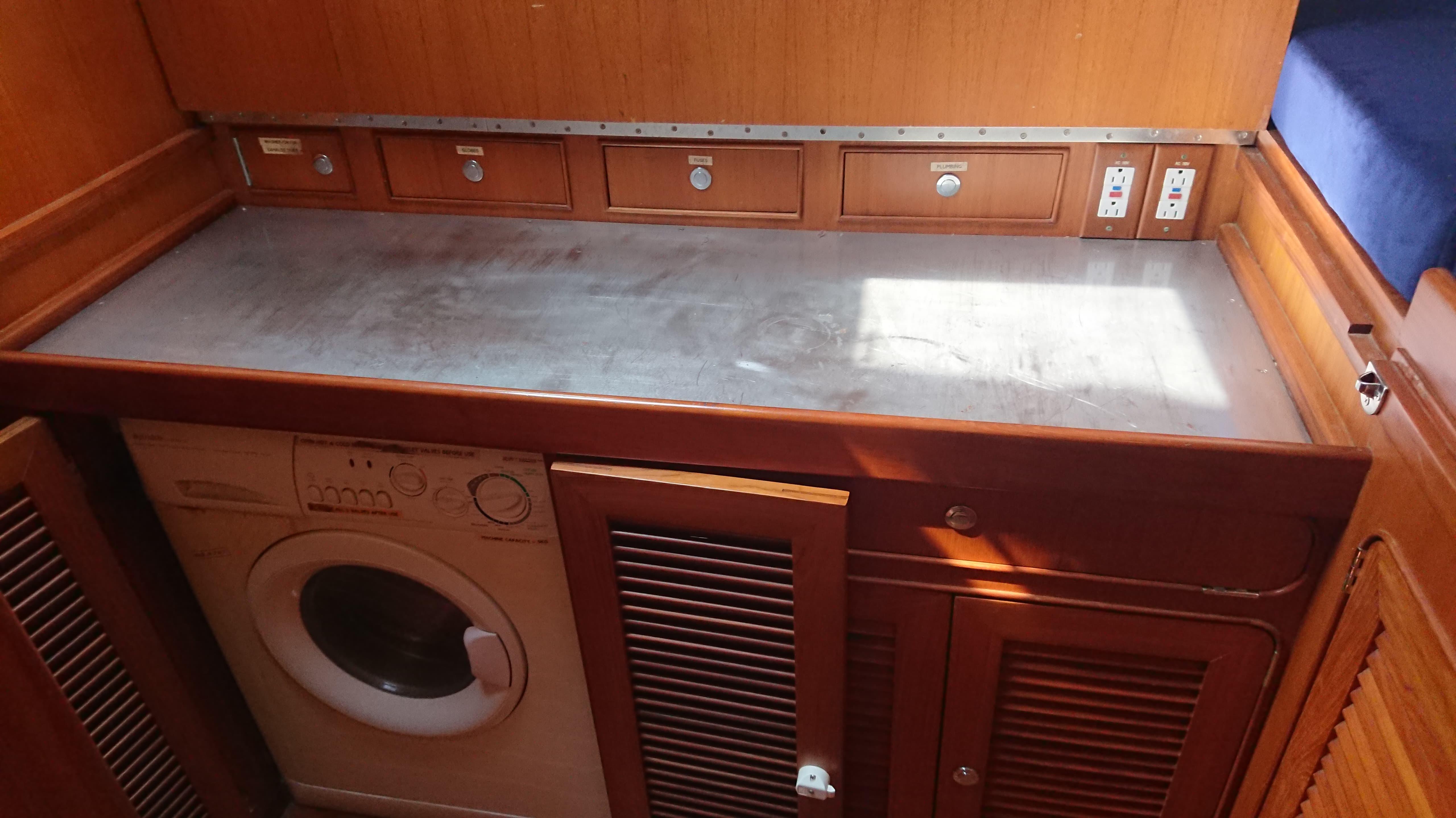 Laundry area in 2004 Hylas H54 yacht with washing machine and wooden cabinetry.