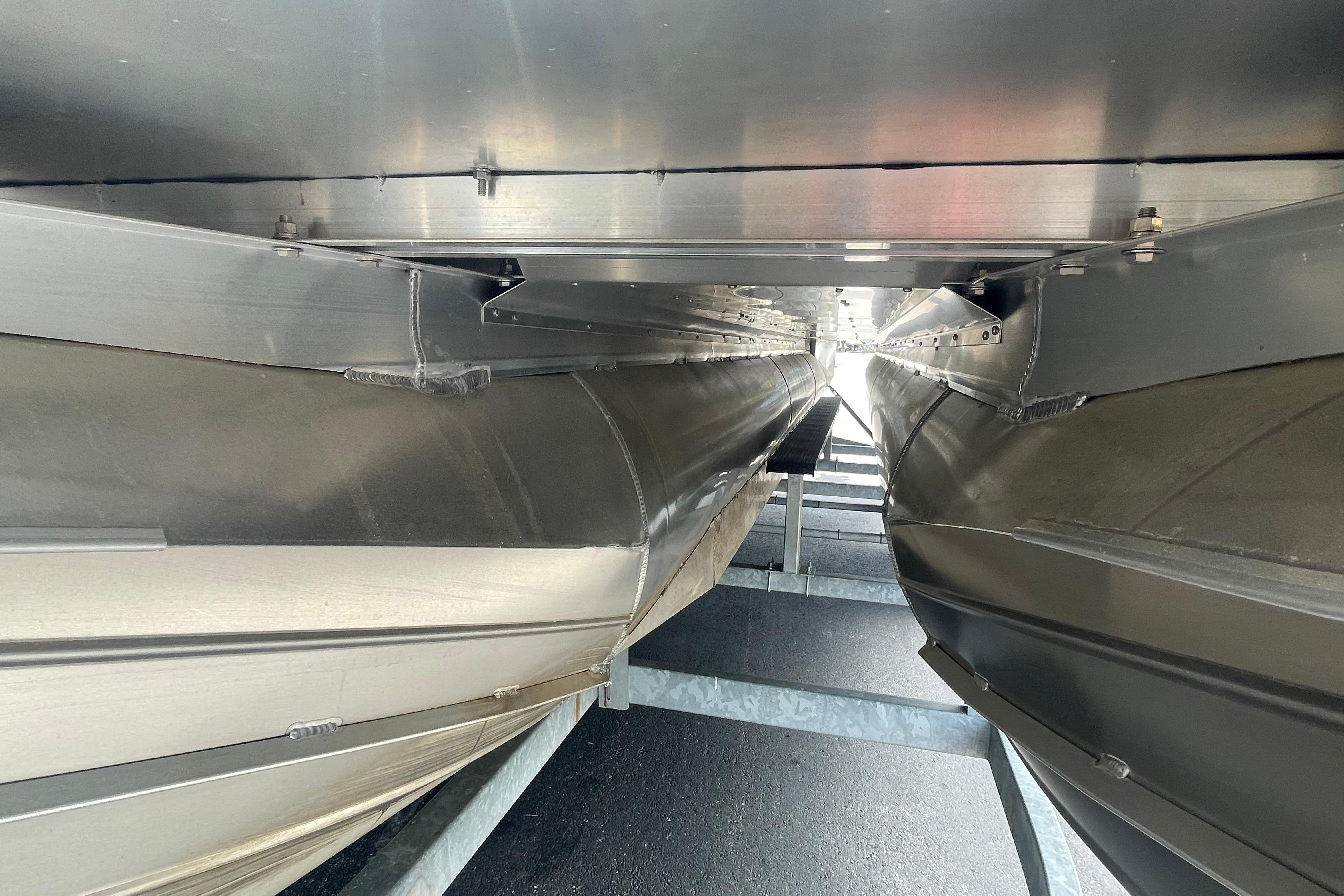 Underneath view of 2022 Manitou 23 Oasis pontoon boat on a trailer.