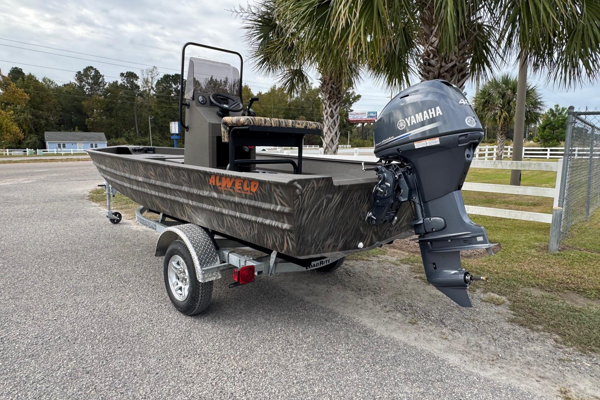 2026 Alweld 1656VV Marsh Console CC boat with Yamaha engine, parked near palm trees.