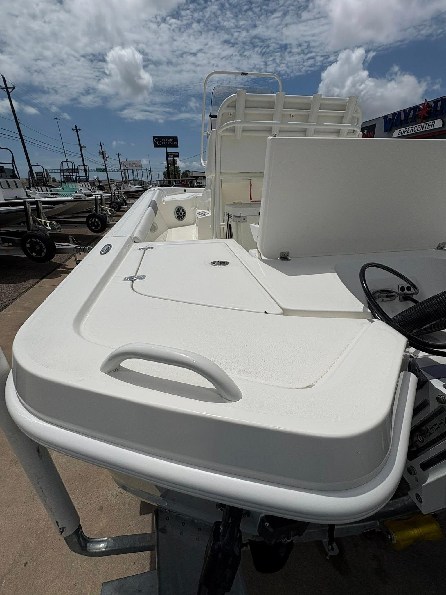 2025 Mako 24 APEX boat deck with storage compartments under a partly cloudy sky.