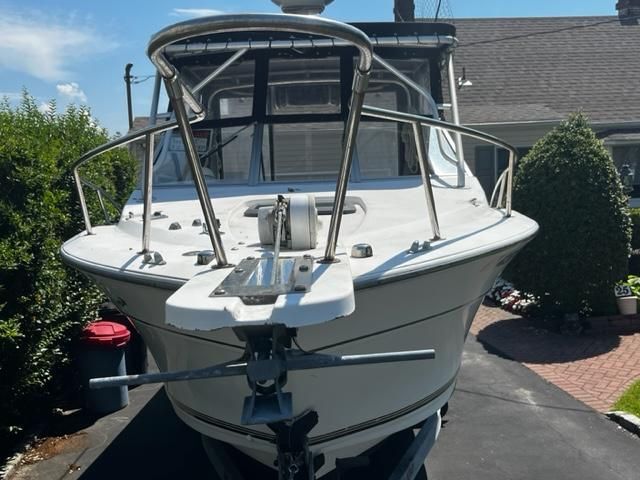 A 1998 Sport-Craft 252 Sport Fish boat is on a trailer in a driveway.