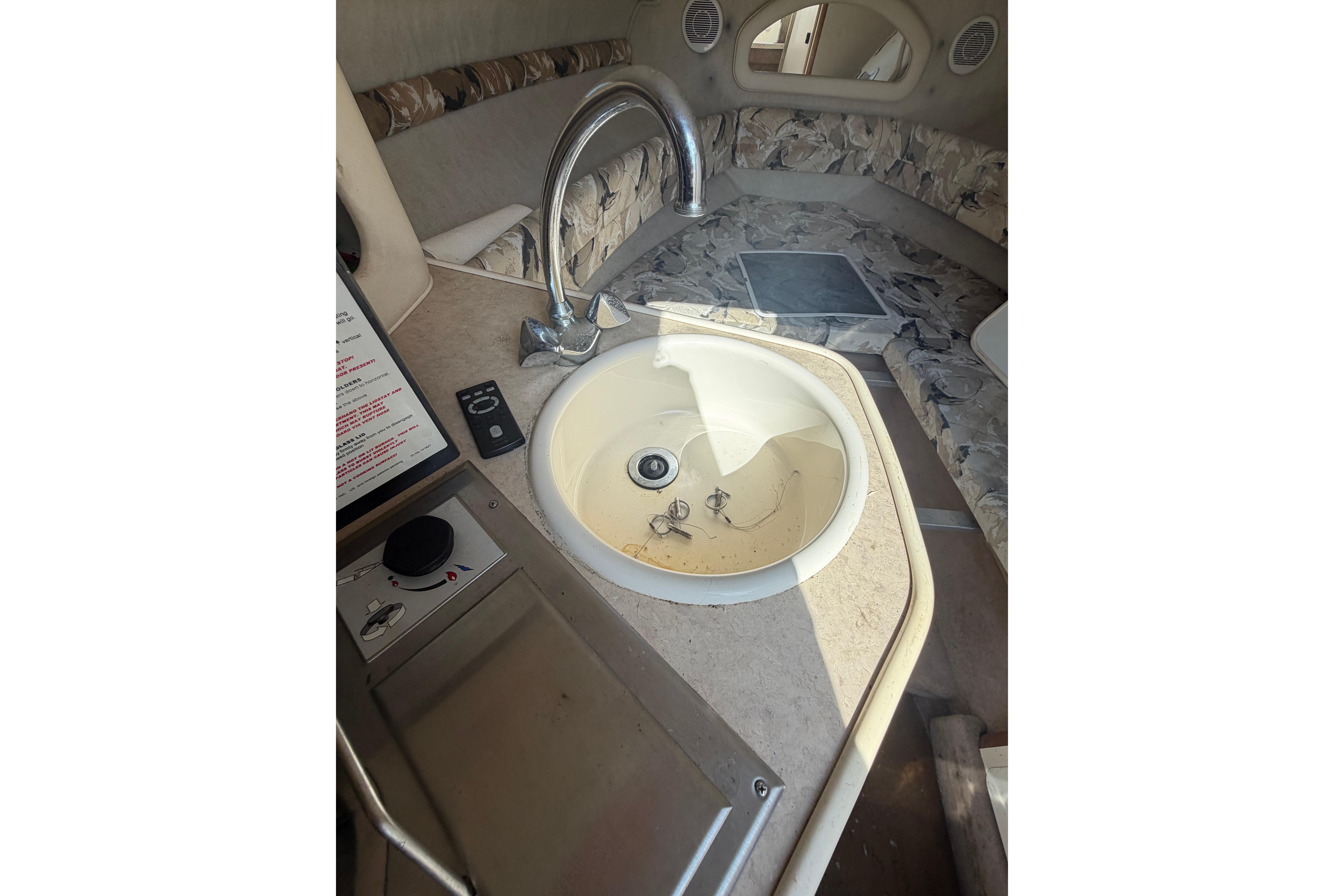 1999 Sea Ray 240 Sundancer interior with sink and seating area.